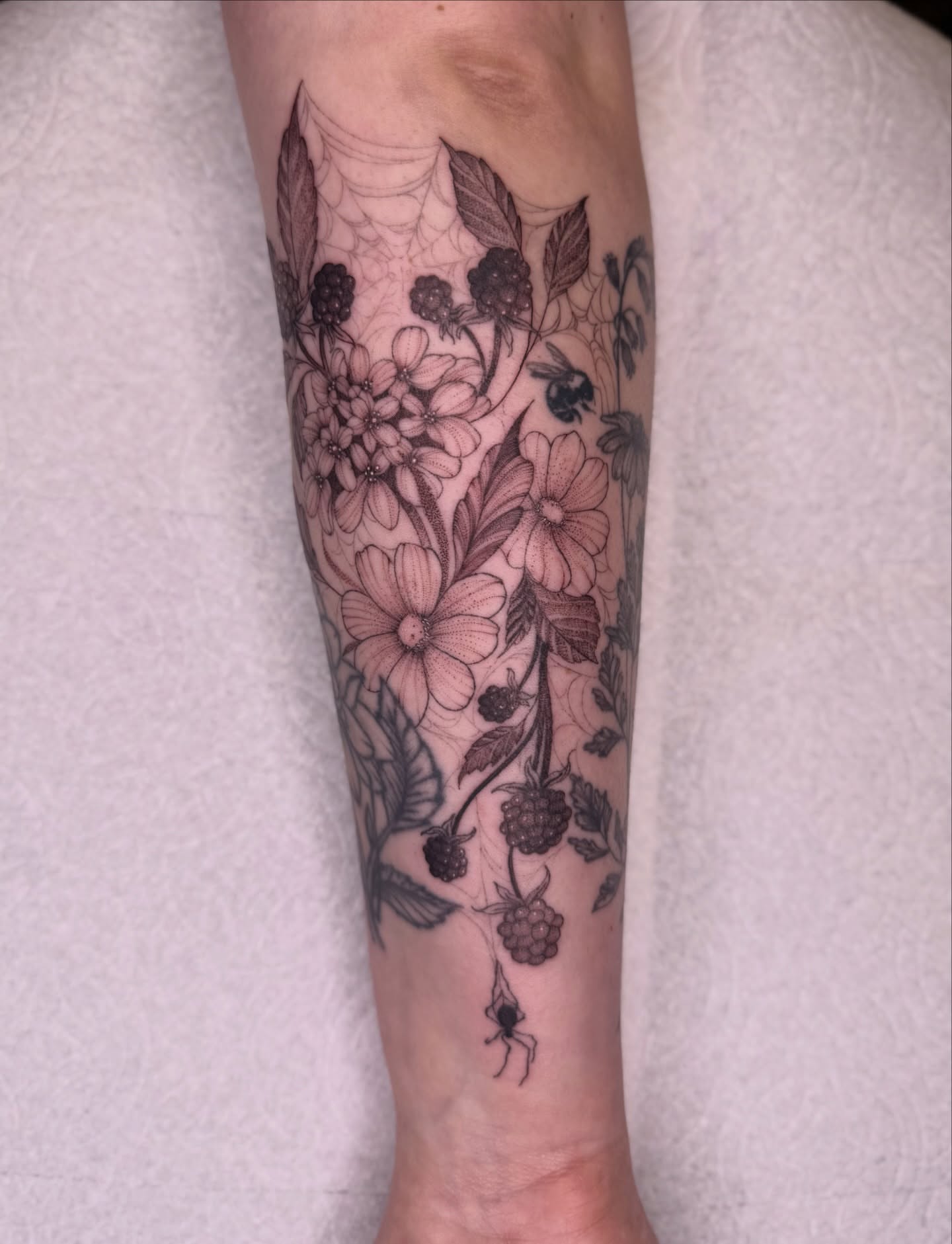 Botanical bouquet realism tattoo on the forearm by Jena Perry