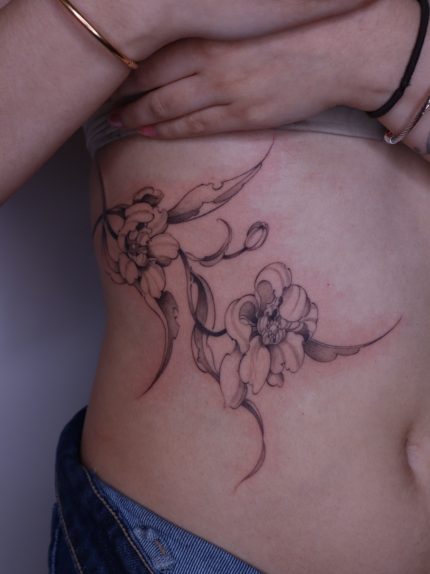 Floral design black and grey tattoo on the ribs by Savana Wang