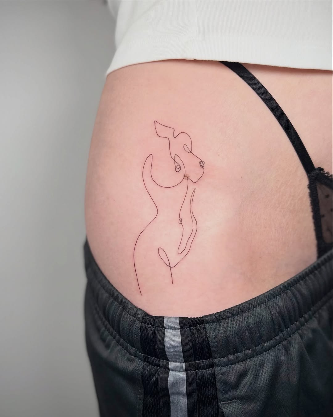 Dog outline minimalist tattoo on the thigh by Jennifer Fuster