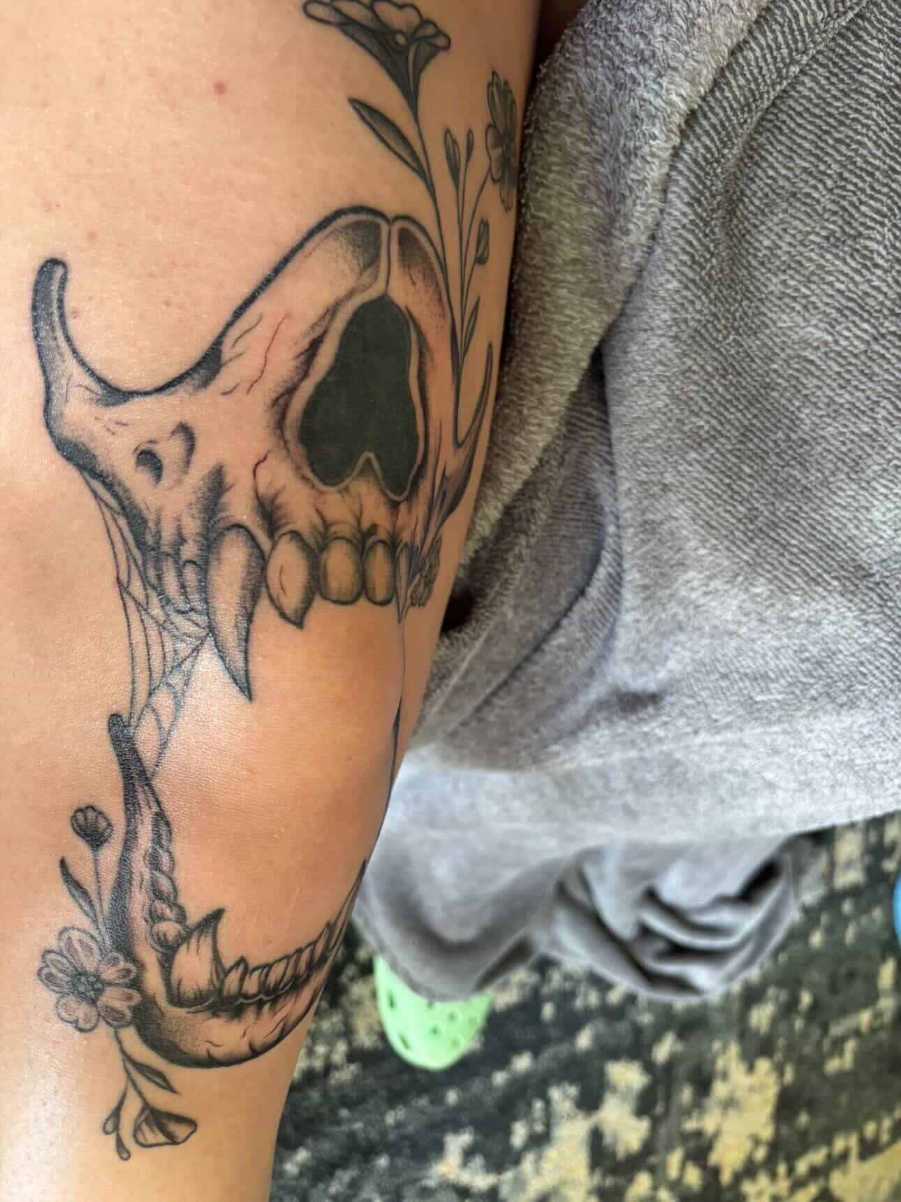 Skull and flowers black and grey tattoo on the forearm by Daniel Smith