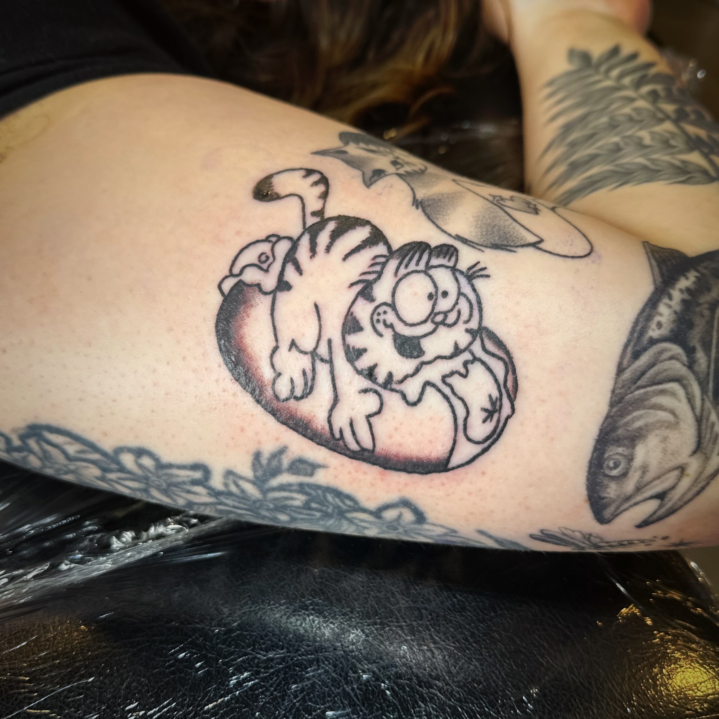 Garfield black and grey tattoo on the upper arm by Madeline Seeley