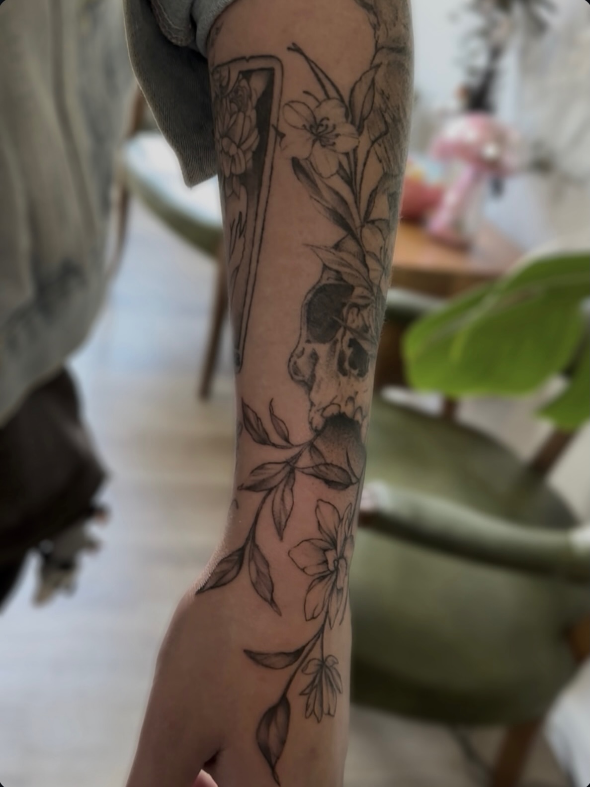 Floral and skull design black and grey tattoo on the forearm by Allexis