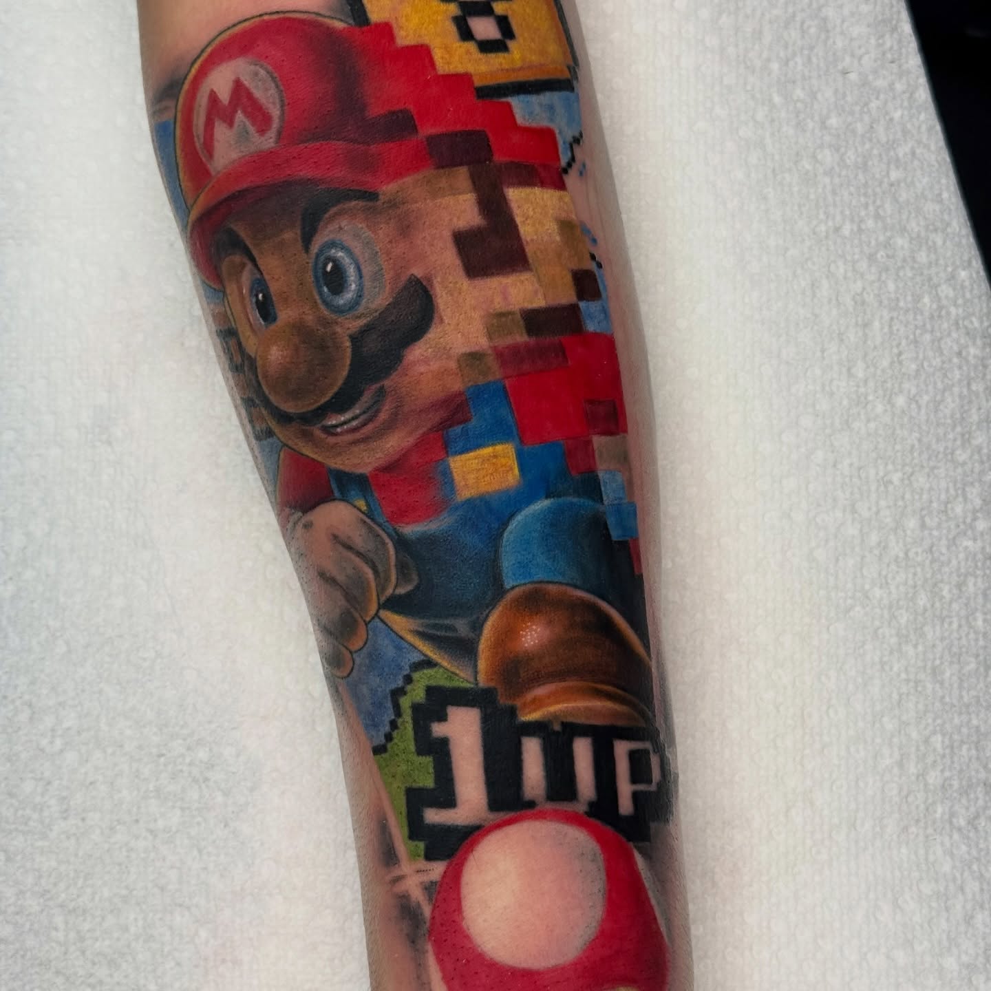 Mario realism tattoo on the forearm by Justin Hay