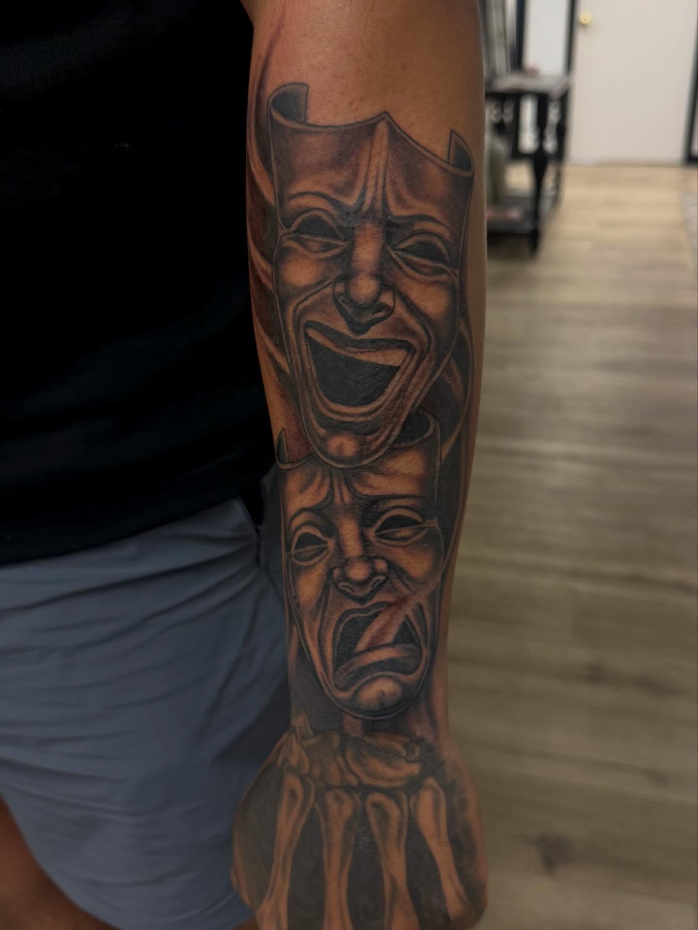 Theater masks black and grey tattoo on the forearm by Gigi