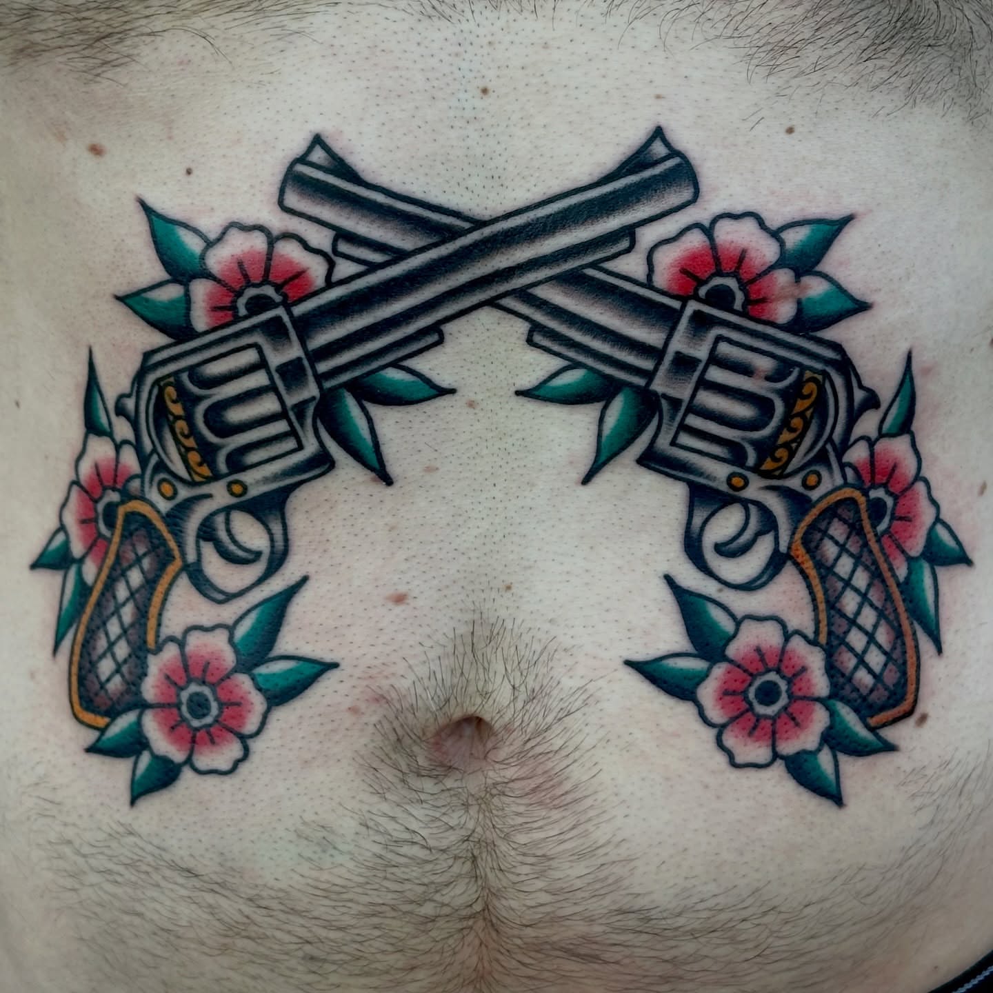 Crossed revolvers and flowers American traditional tattoo on the chest by Amanda Bonhomme, Las Vegas, Nevada