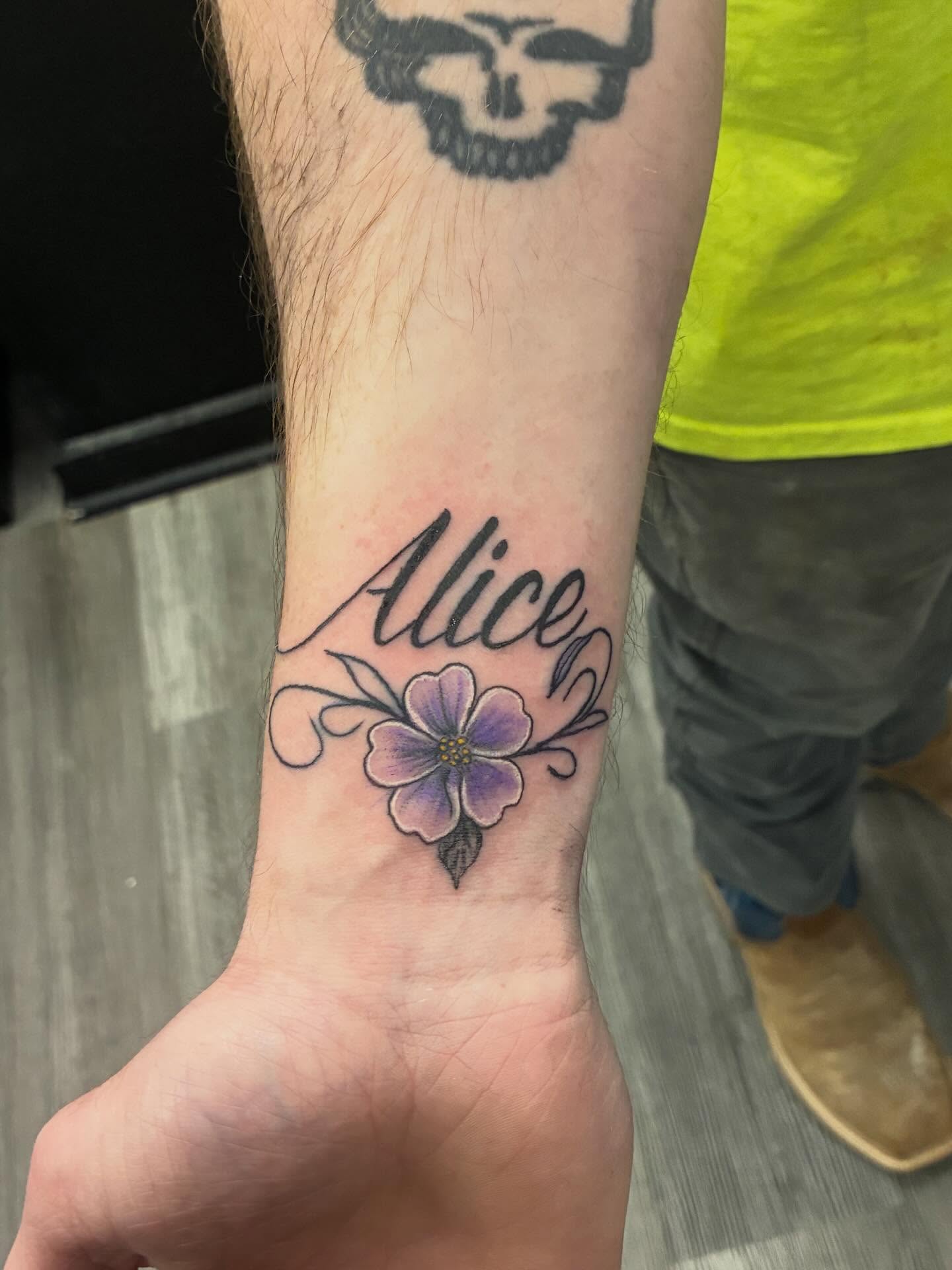 Flower and name new school tattoo on the forearm by Trae