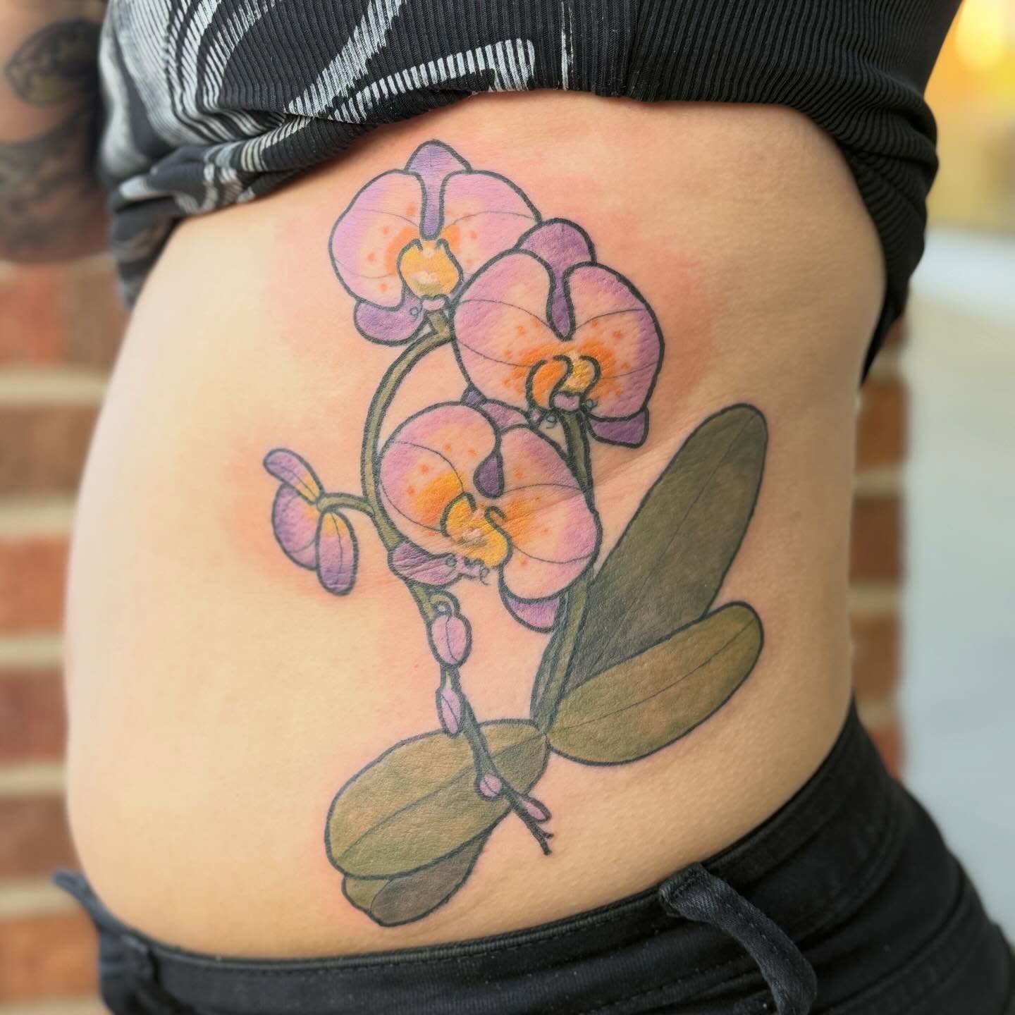 Orchid watercolor tattoo on the torso by Erin McDavis