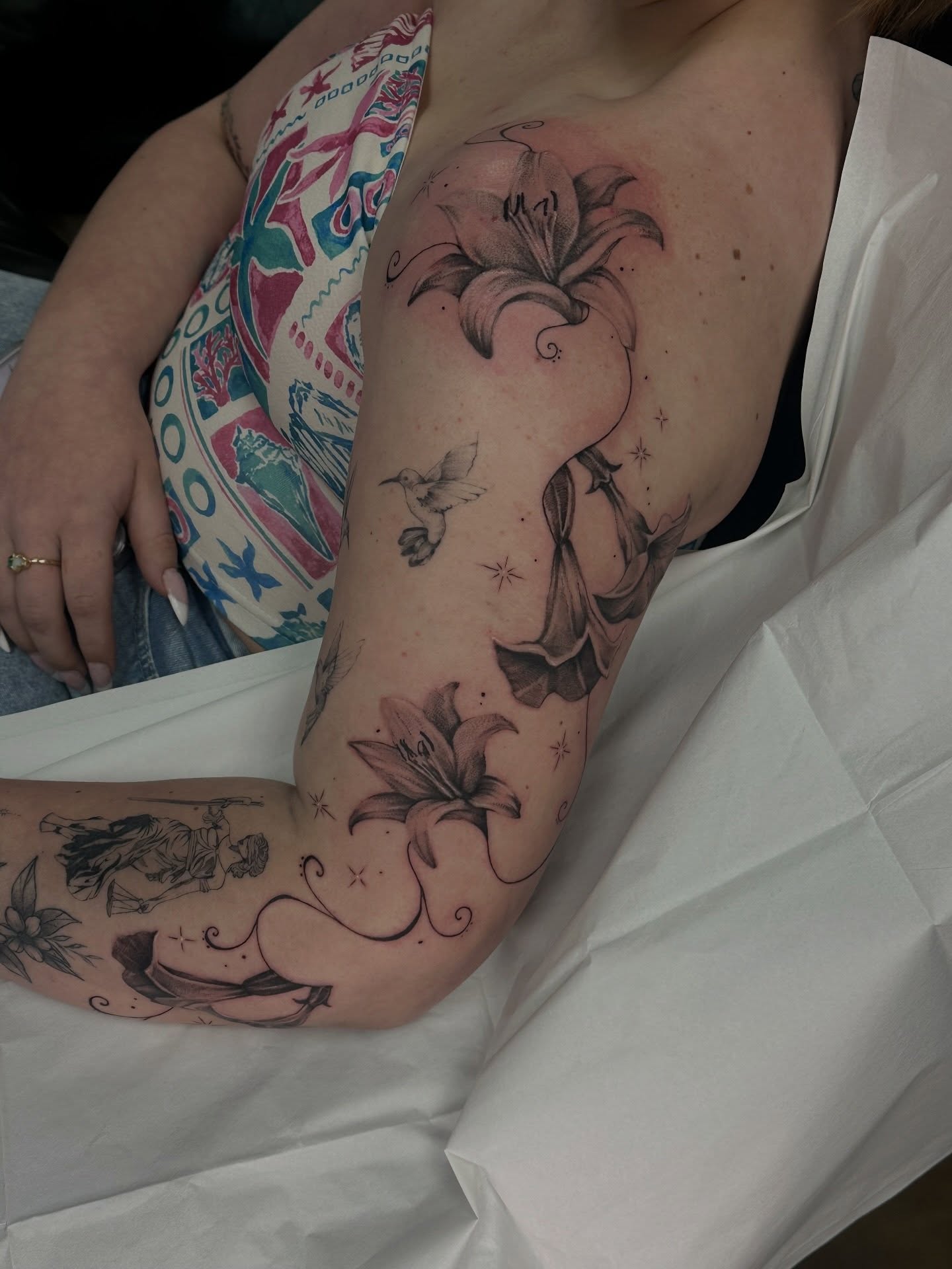 Lily flowers black and grey tattoo on the upper arm by Halle Cooper