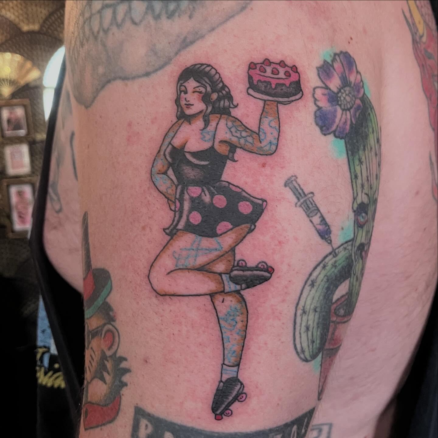 Pin-up girl with cake American traditional tattoo on the upper arm by madelynne (maddie) caldwell tattoos
