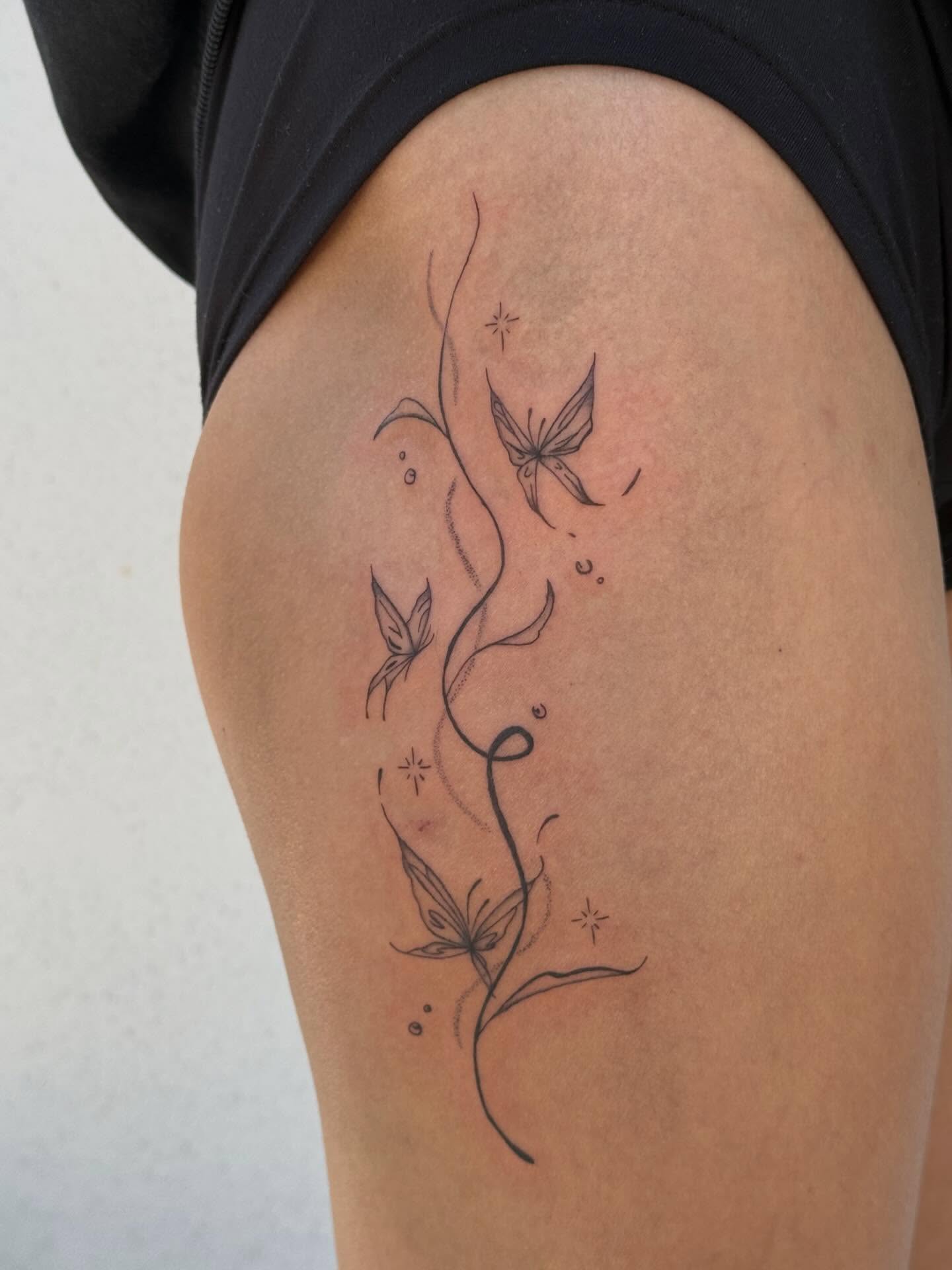 Butterfly and vine fine line tattoo on the thigh by TATTOO & PIERCING ARTIST ₊˚⊹ ᰔ