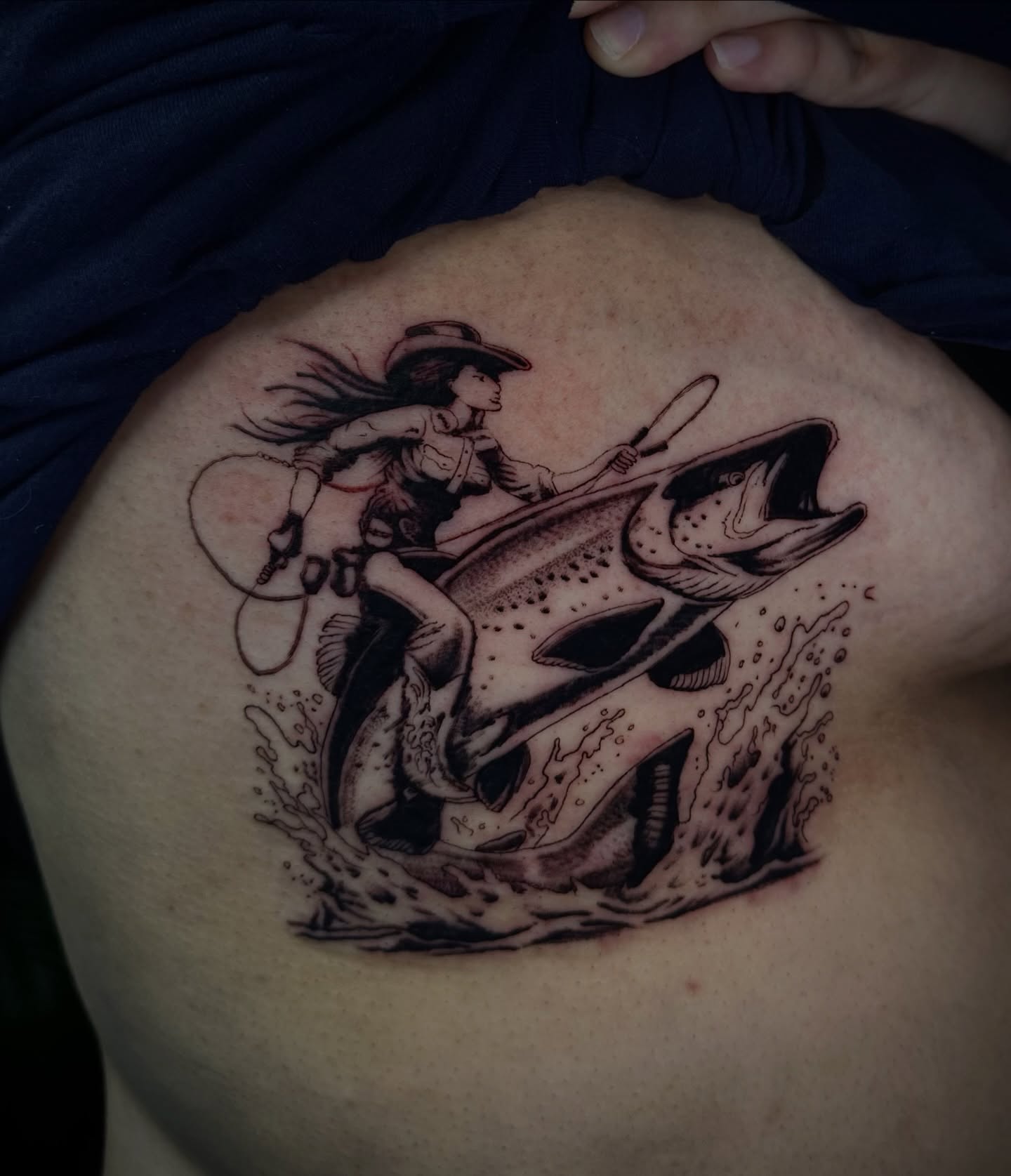 Cowgirl riding a fish black and grey tattoo on the ribs by Angel Tattoos