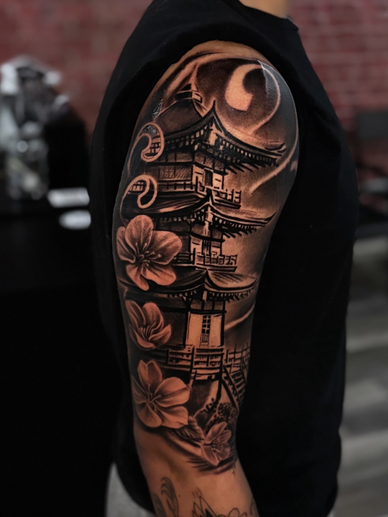 Cherry blossoms and pagoda realism tattoo on the forearm by Miguel Garcia