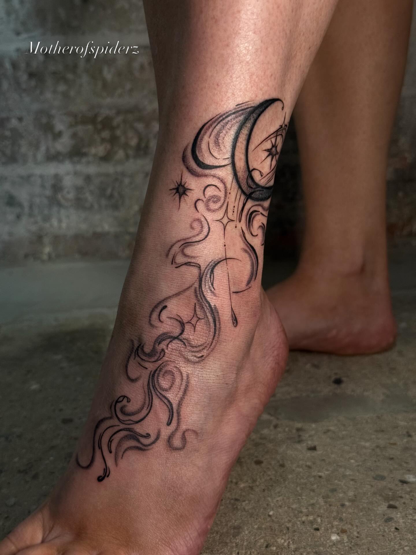 Swirling crescent moon and stars black and grey tattoo on the foot by Alyssa Garza