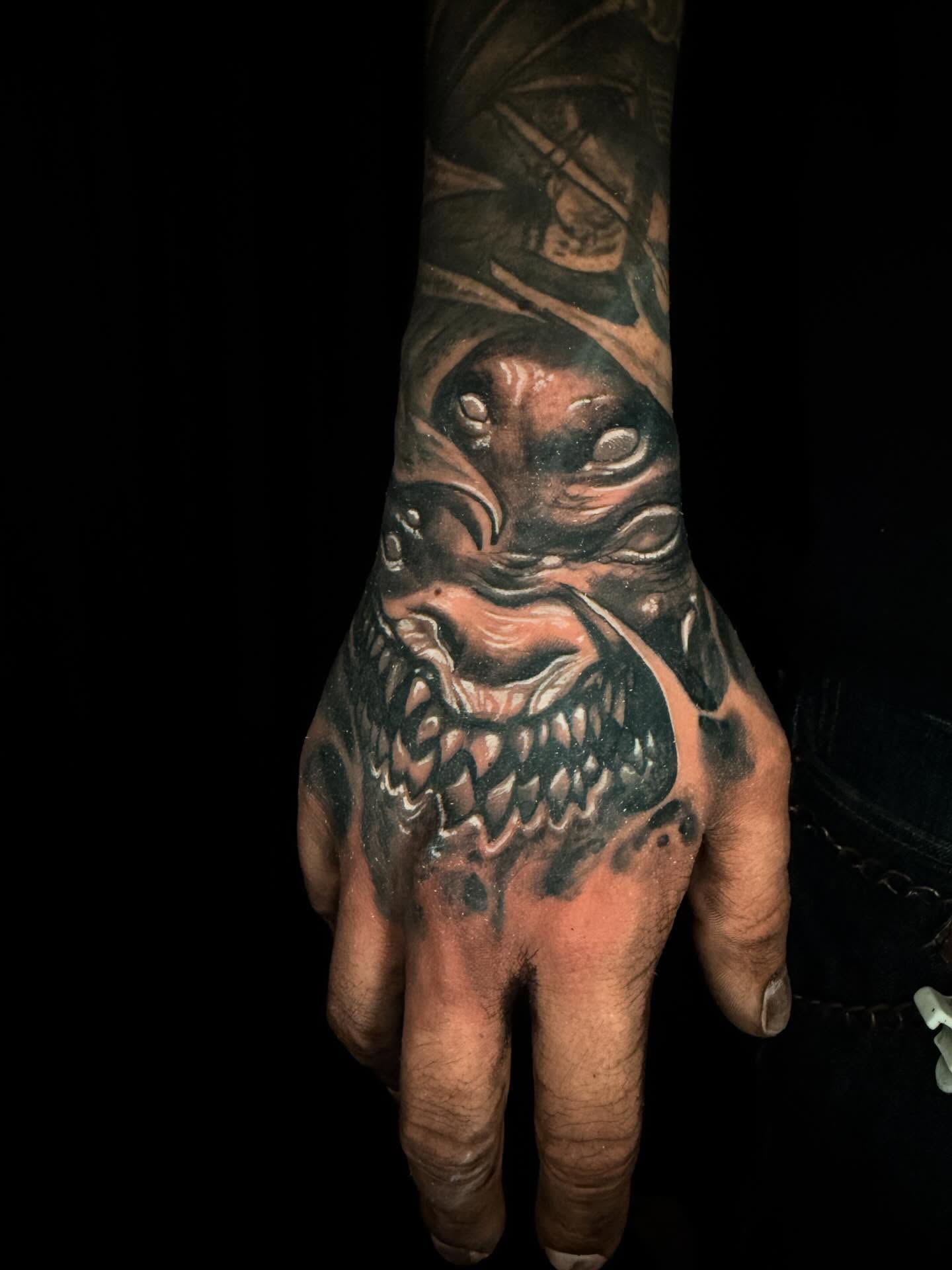 Demon face dark realism tattoo on the hand by Bruno Moretti