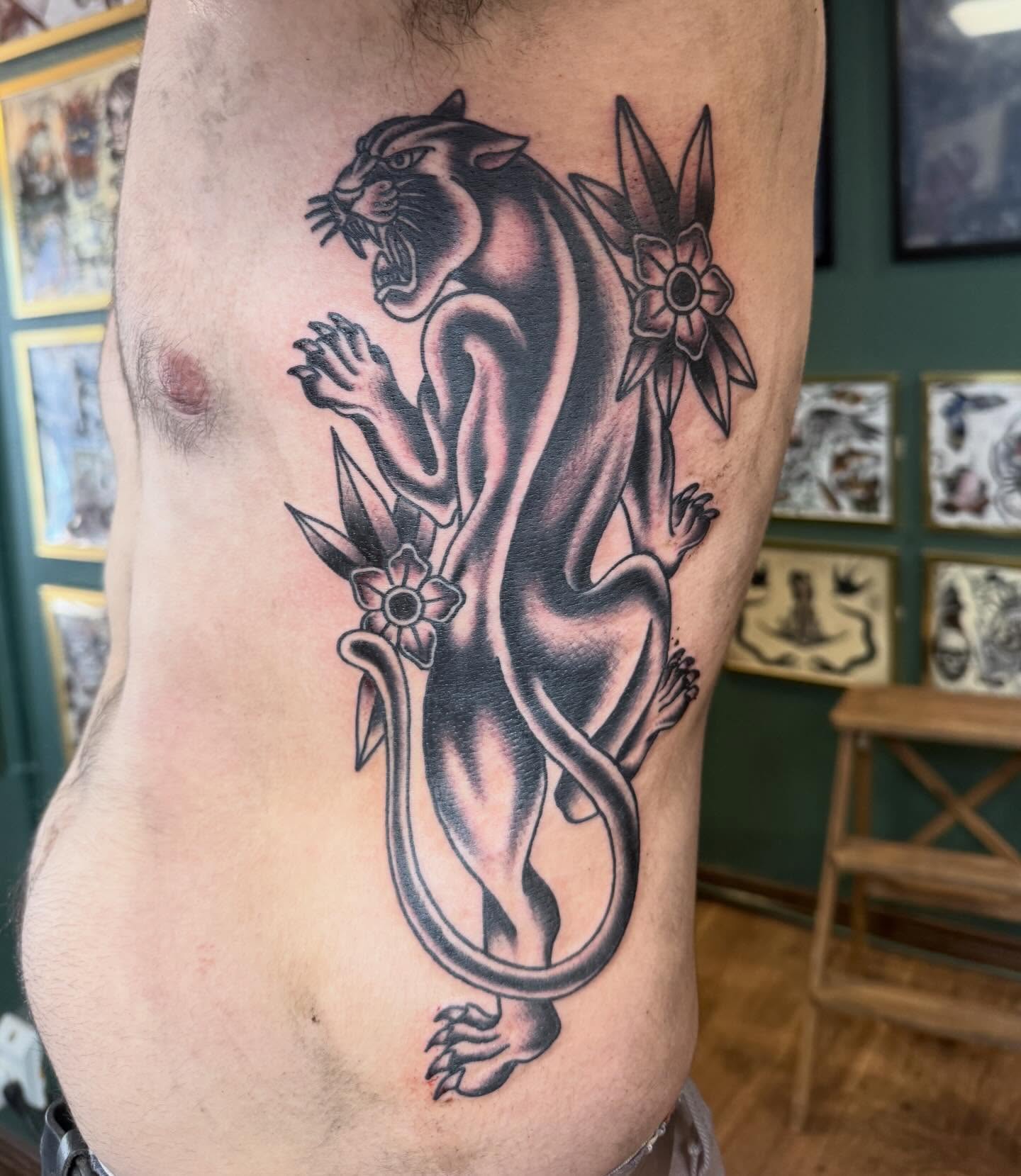 Panther with flowers black and grey tattoo on the ribs by Ryan Moraski, Colorado Springs, Colorado