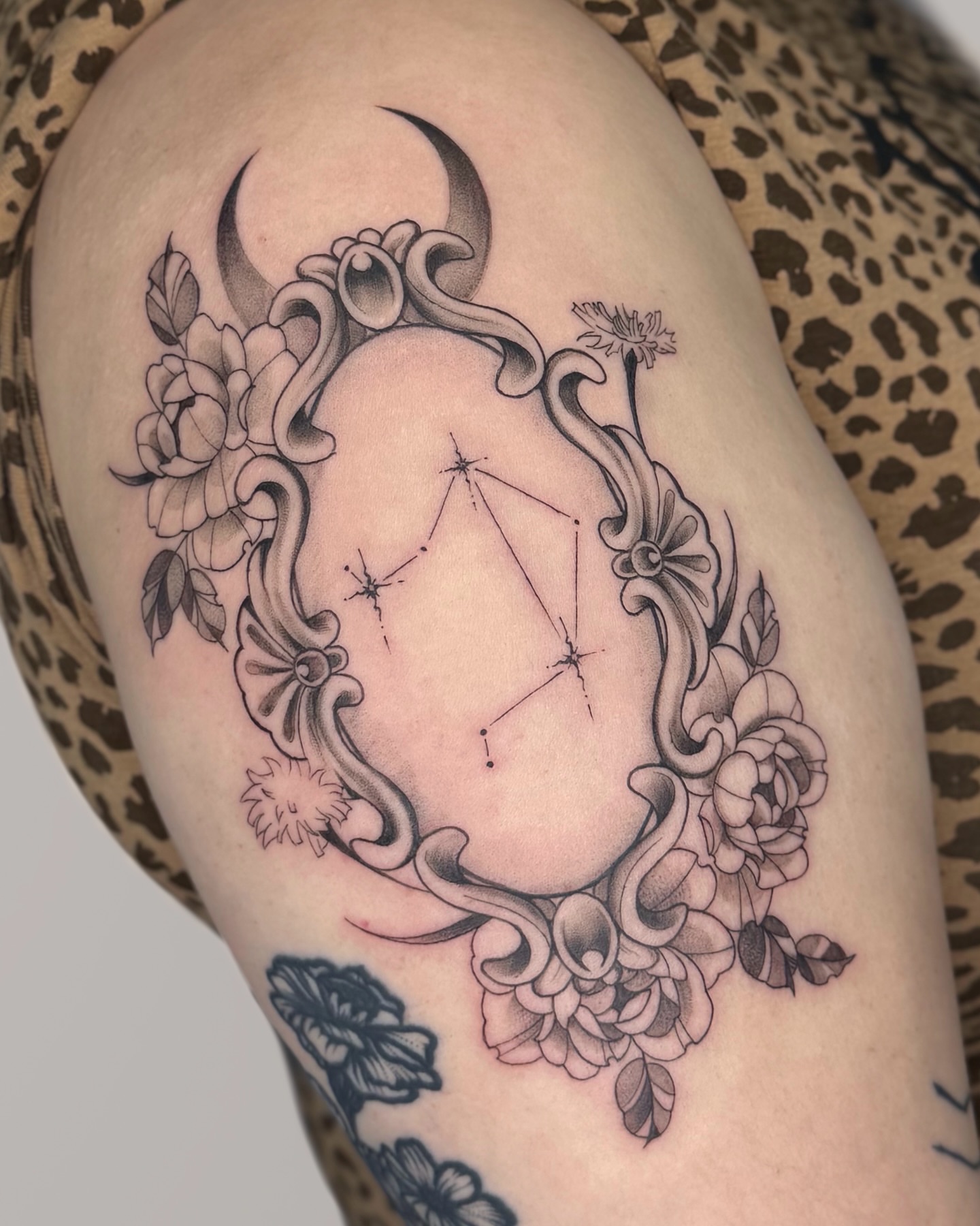 Constellation within floral frame ornamental tattoo on the thigh by Suzy