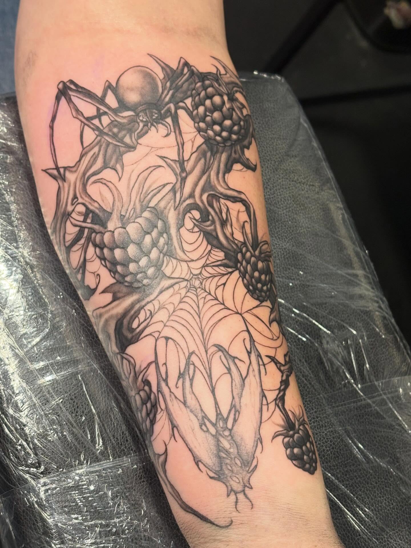 Pineapple and spider black and grey tattoo on the forearm by Slade Nowicki