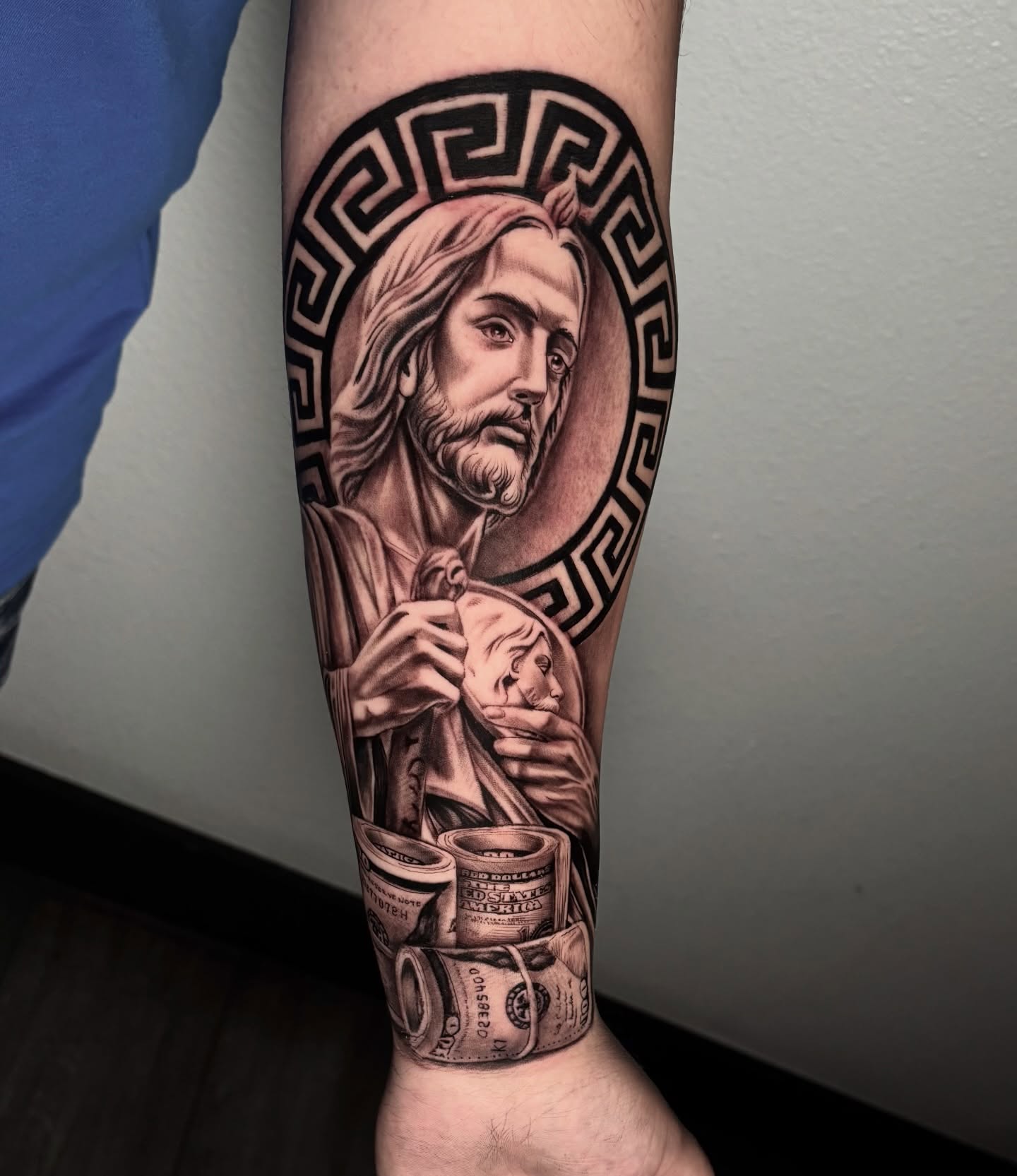 Religious figure with money realism tattoo on the forearm by Dave