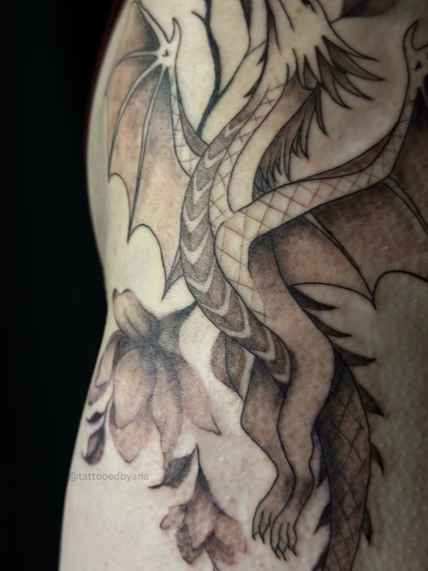 Dragon black and grey tattoo on the upper arm by Tattoo artist Denver