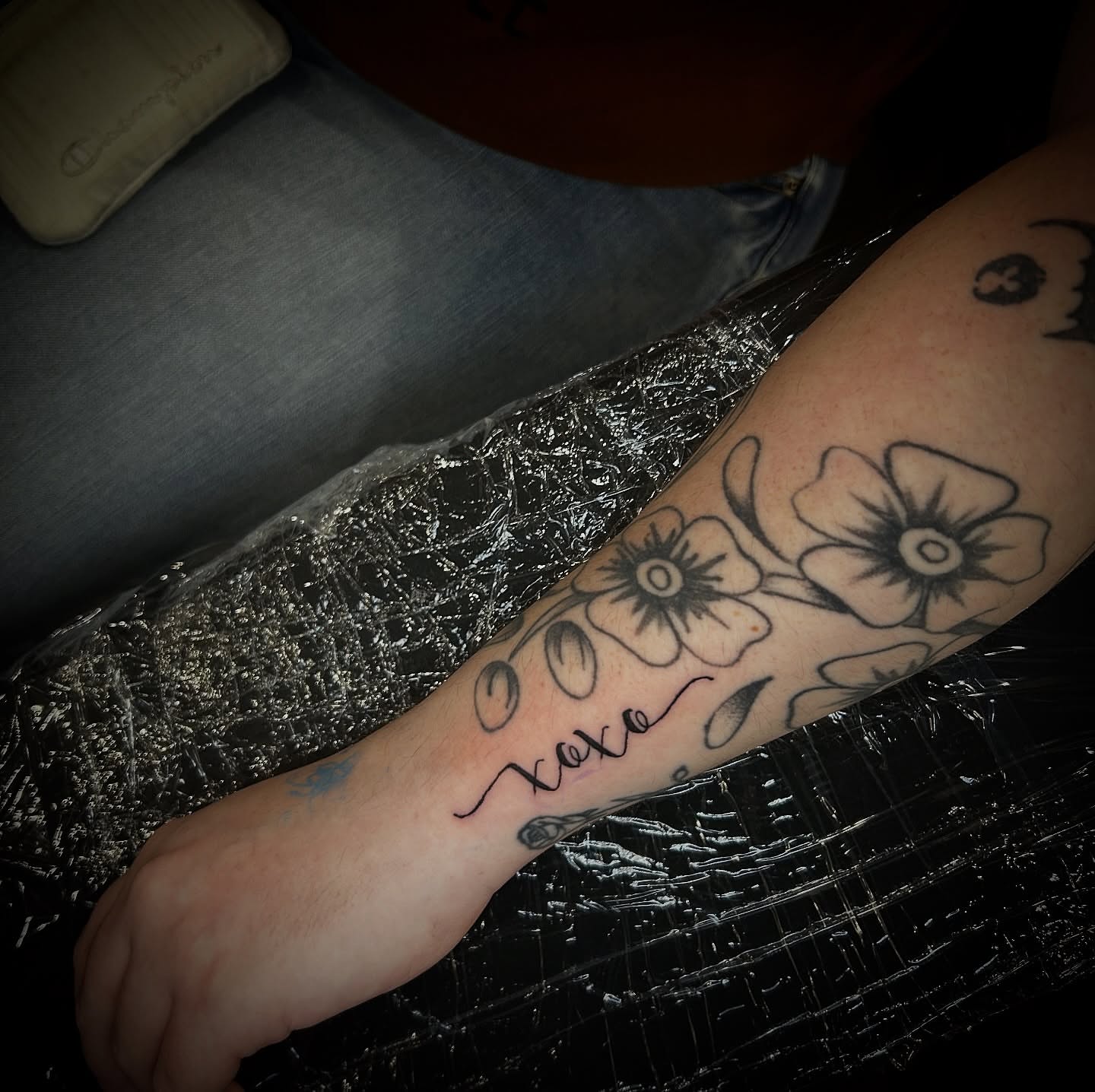 Flowers and 'xoxo' black and grey tattoo on the forearm by Porshamonie' THE Tattoo ARTIST