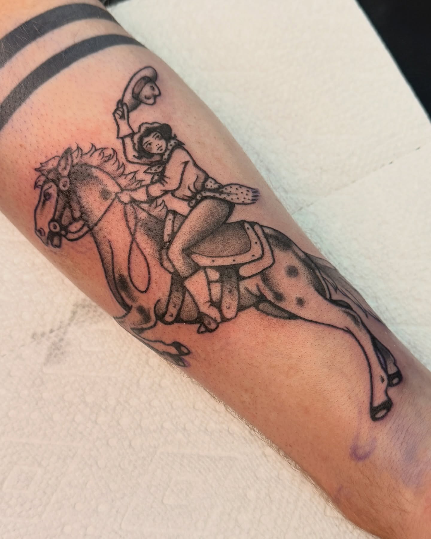 Cowboy riding horse black and grey tattoo on the forearm by Penny D Tattoos