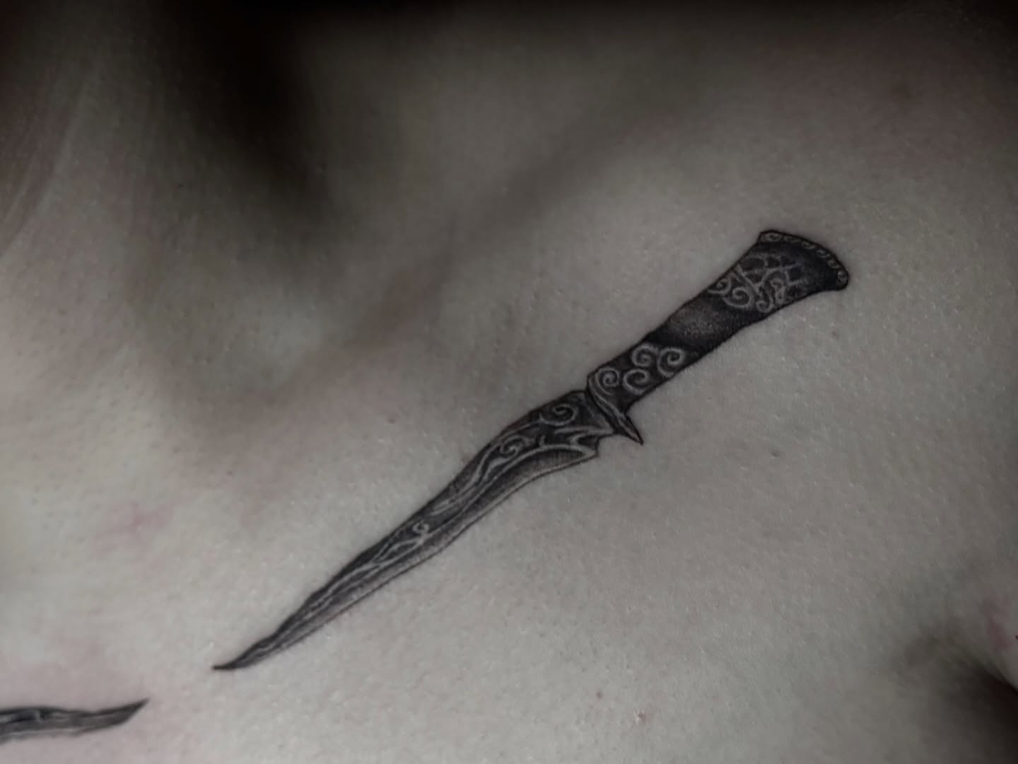 Knife black and grey tattoo on the chest by 𝒜𝓇𝓉 𝒷𝓎 𝒱𝑒 𝒩𝑜𝒸𝓉𝑒𝓂