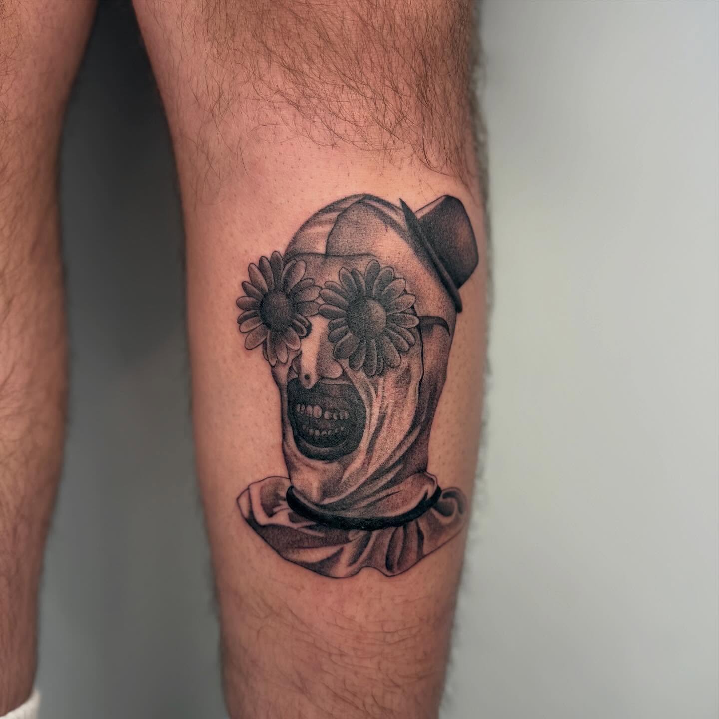 Clown with flowers black and grey tattoo on the forearm by H e I D I