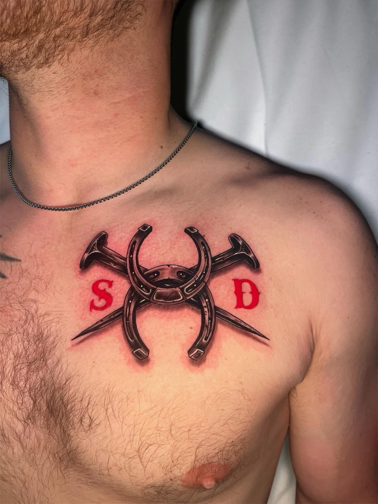 Horseshoe and nails geometric tattoo on the chest by Brooke Kresco