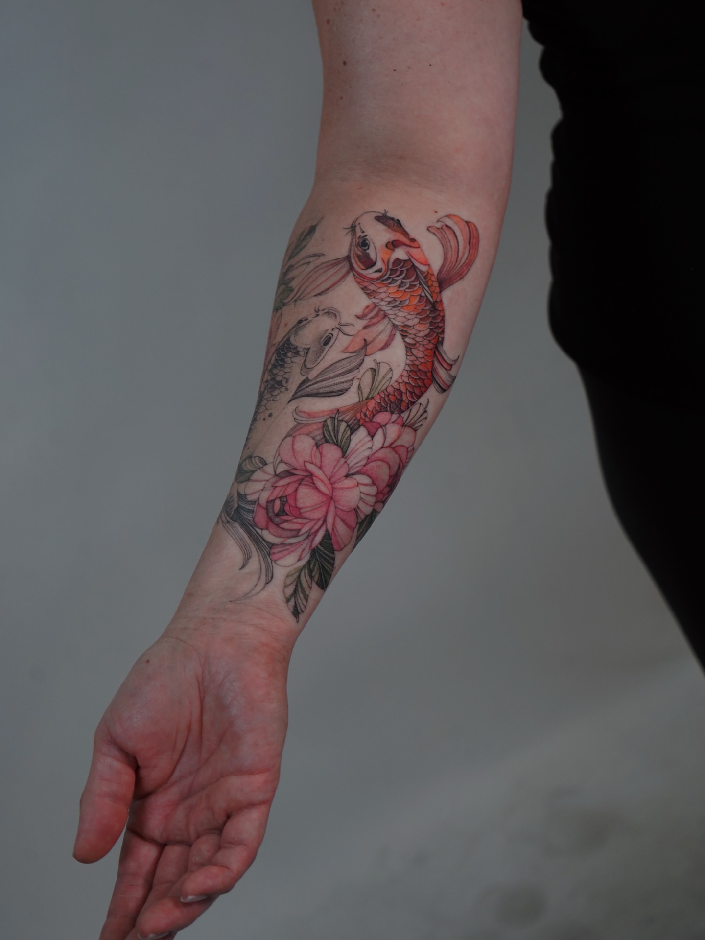 Koi fish and flowers realism tattoo on the forearm by Flower Tattoo Sf