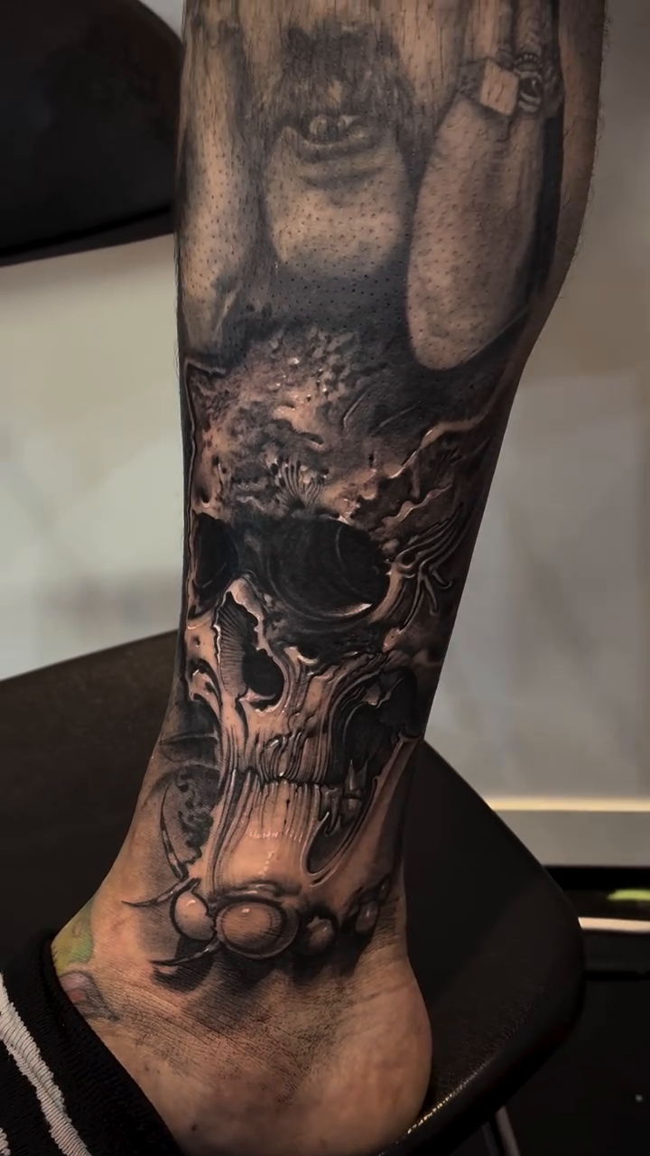 Skull with chains and figures dark realism tattoo by Robert Hernandez