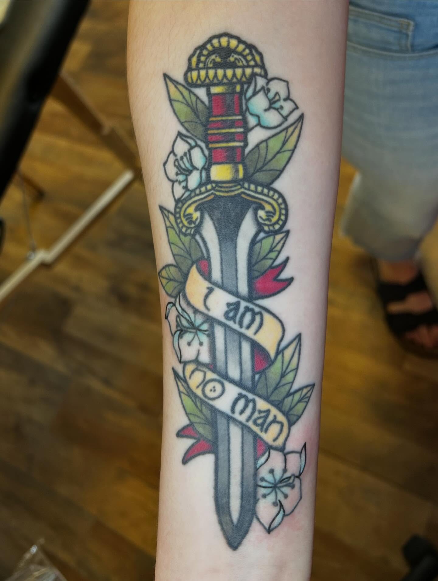 Sword and floral banner American traditional tattoo on the forearm by Alexis Skye