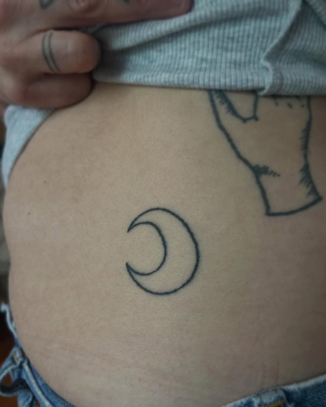 Crescent moon minimalist tattoo on the torso by Emma D