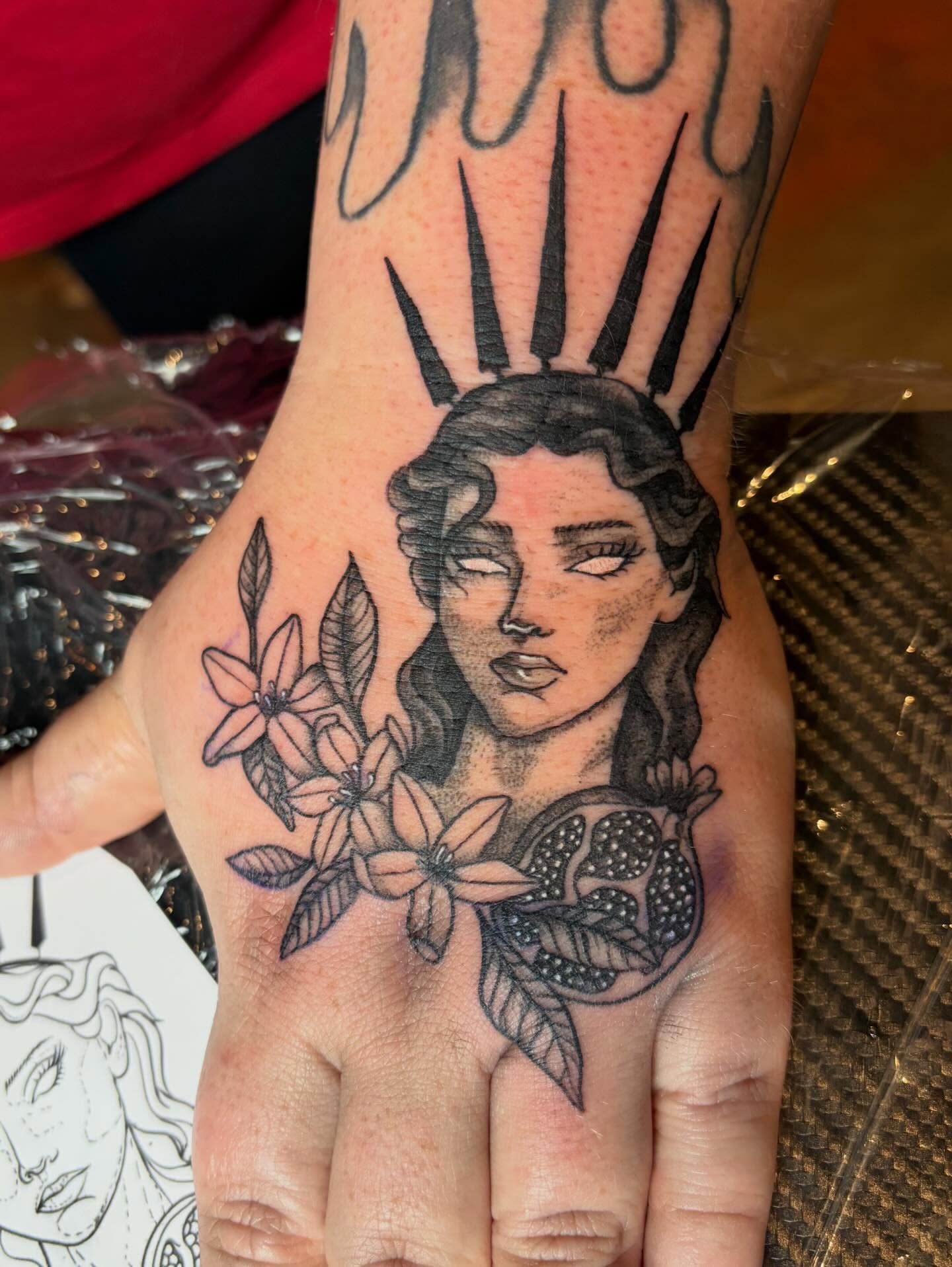 Woman with flowers and pomegranate realism tattoo on the hand by destany aguilera, Davenport, Iowa