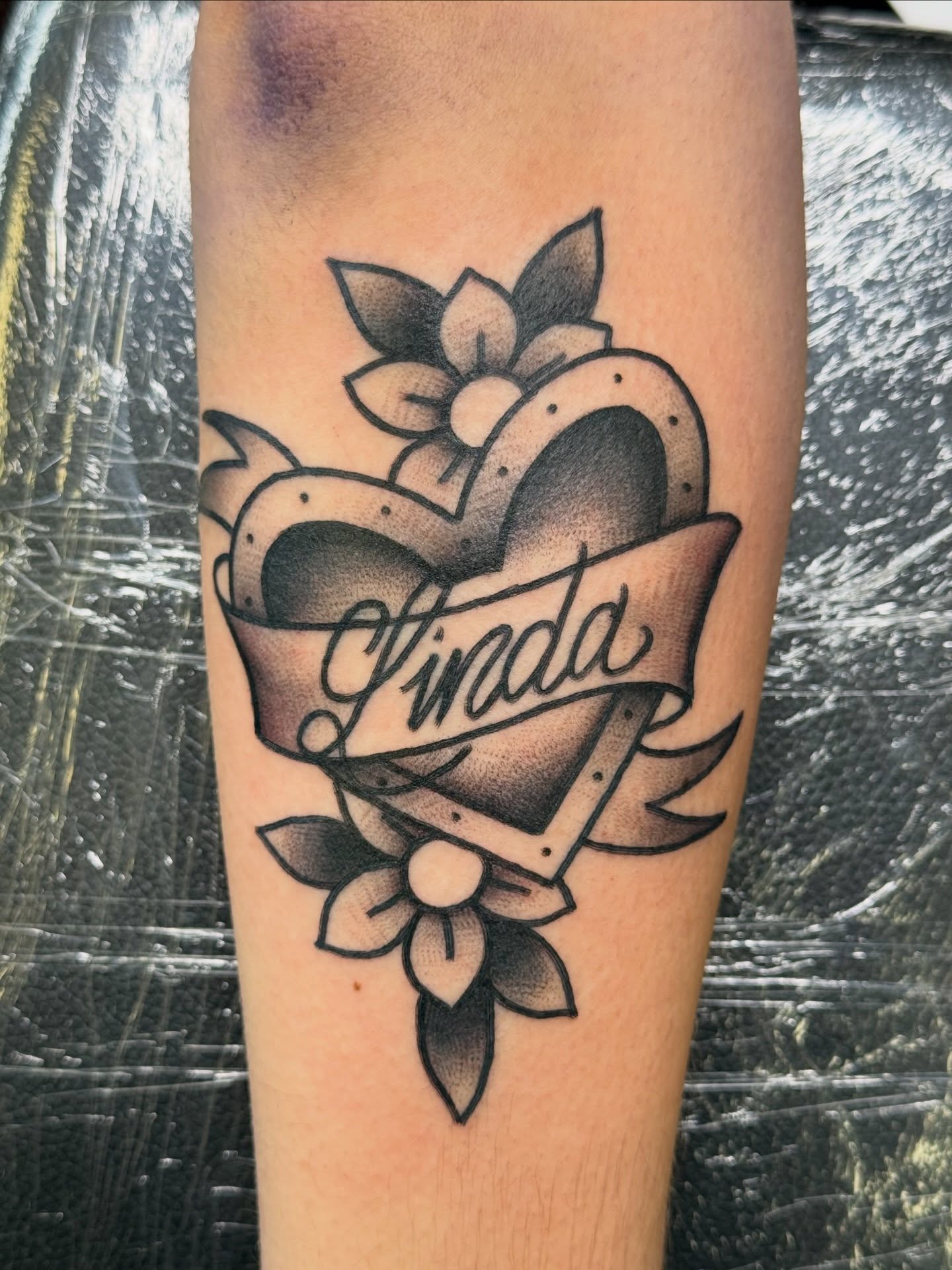Heart with ribbon American traditional tattoo on the forearm by Kelsey Louis, Iowa City, Iowa