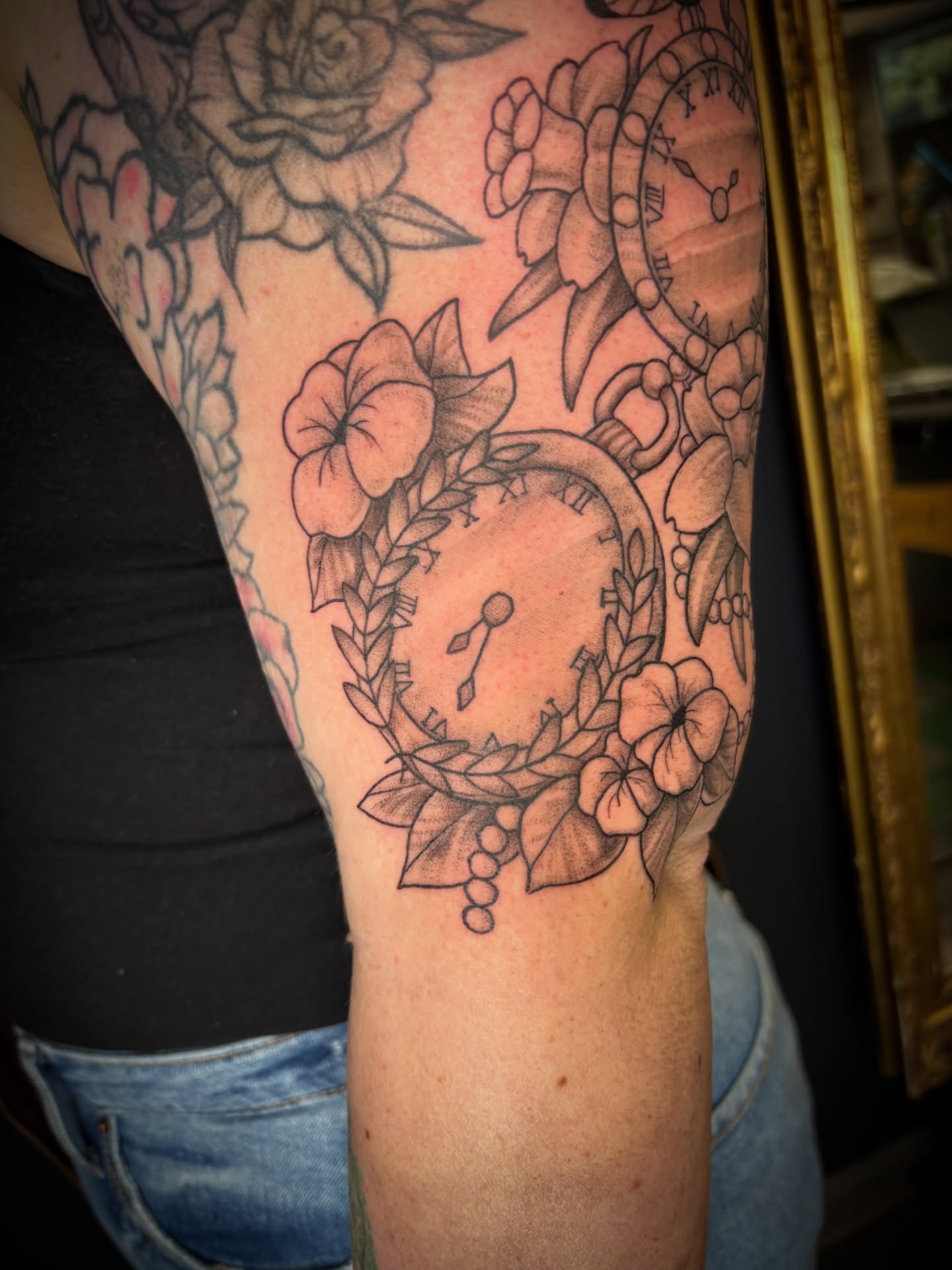 Clock and floral wreath black and grey tattoo on the forearm by Noah Blum