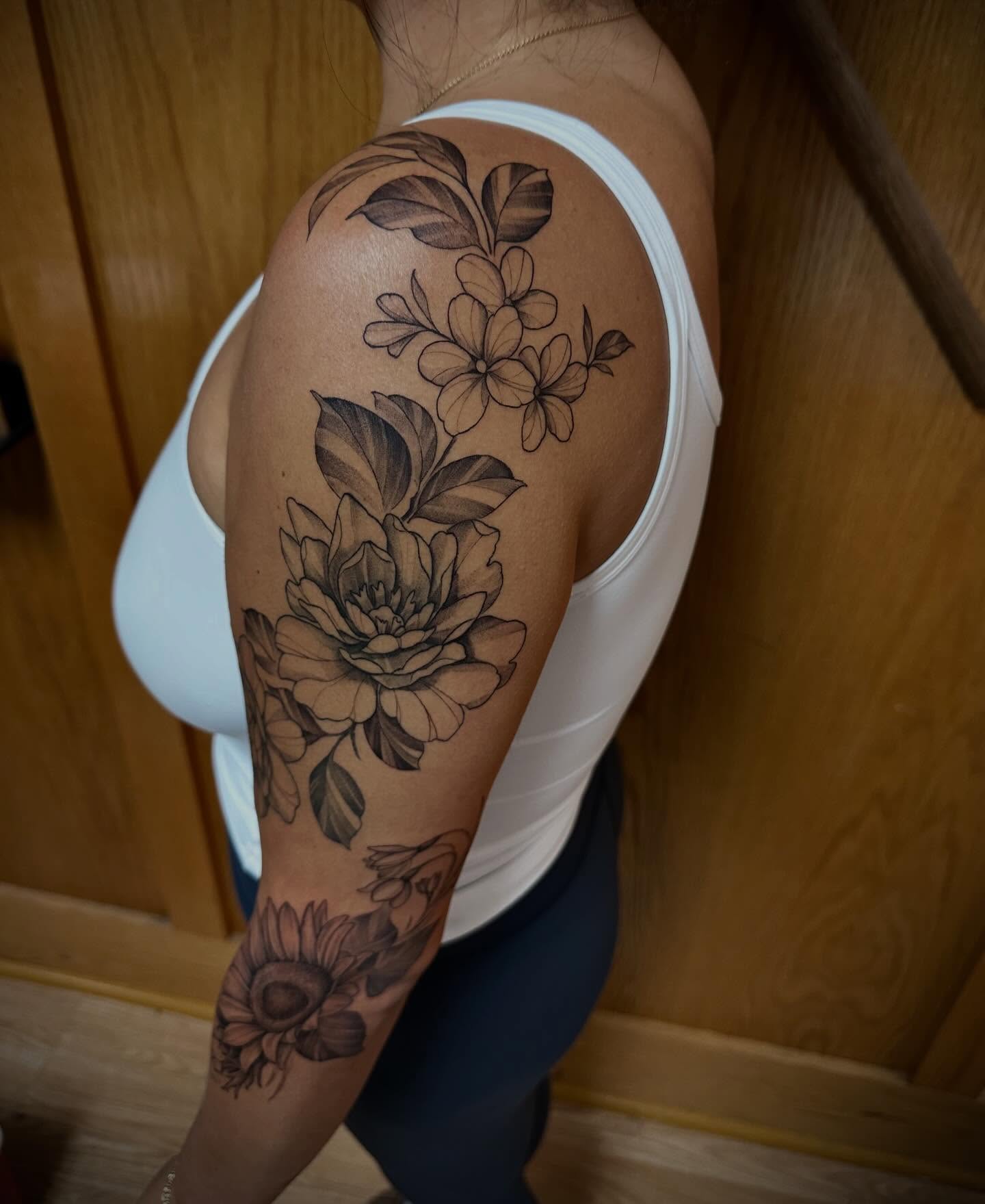 Floral arrangement black and grey tattoo on the upper arm by Sebastian Livingston