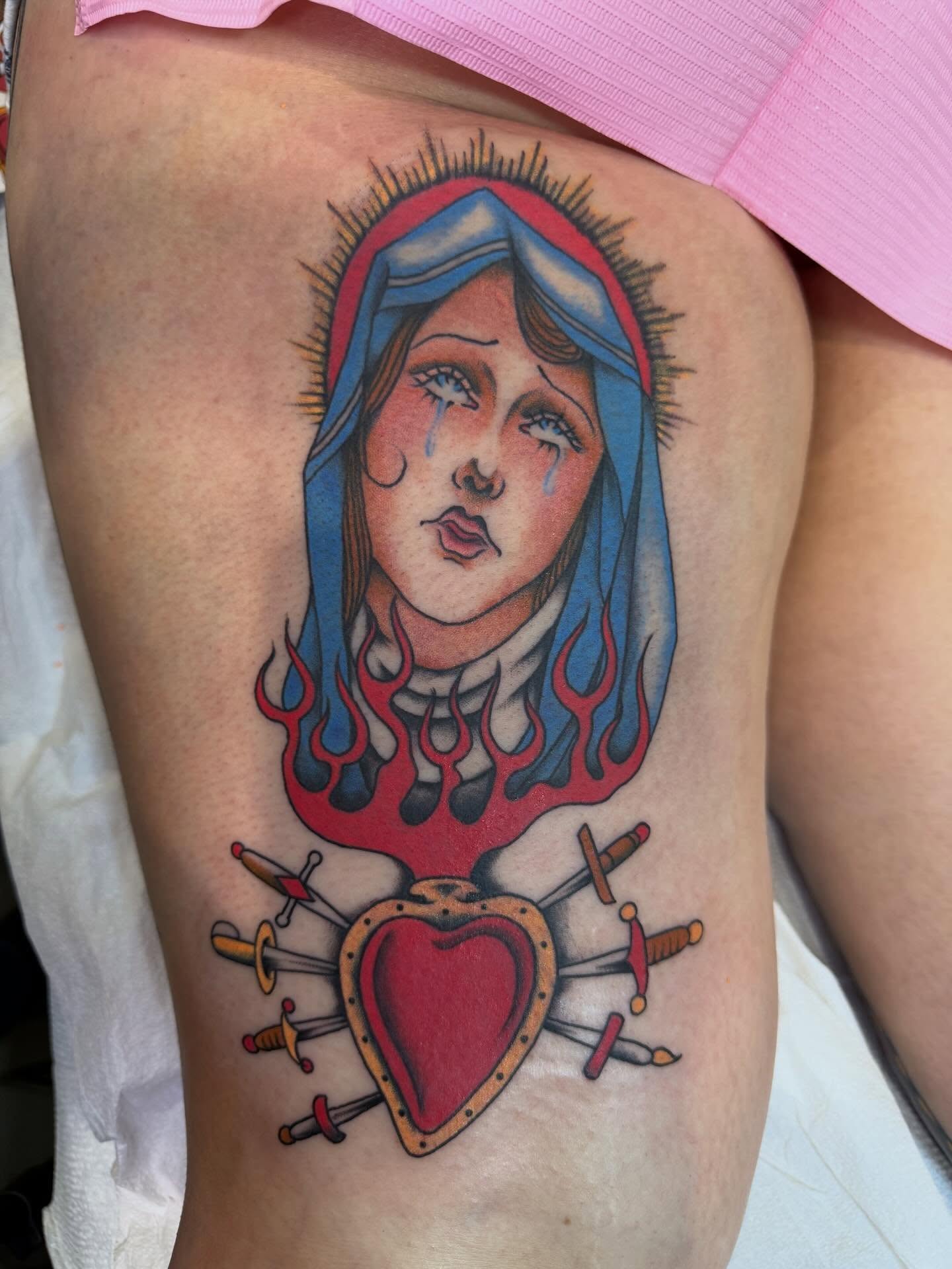 Religious figure with heart American traditional tattoo on the thigh by Mikaila Rose Krauss