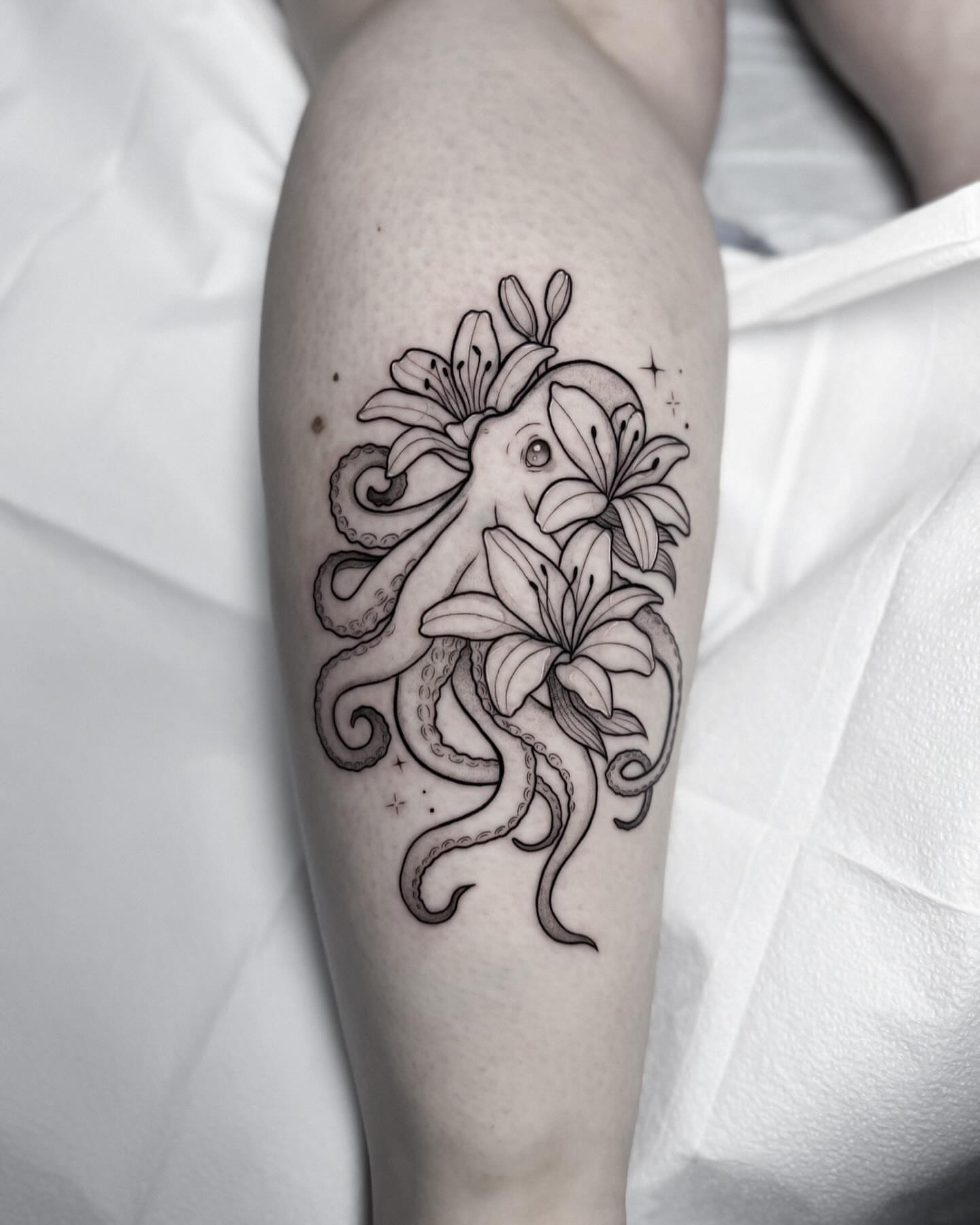 Octopus and lilies realism tattoo on the forearm by Whimsical Tattoos