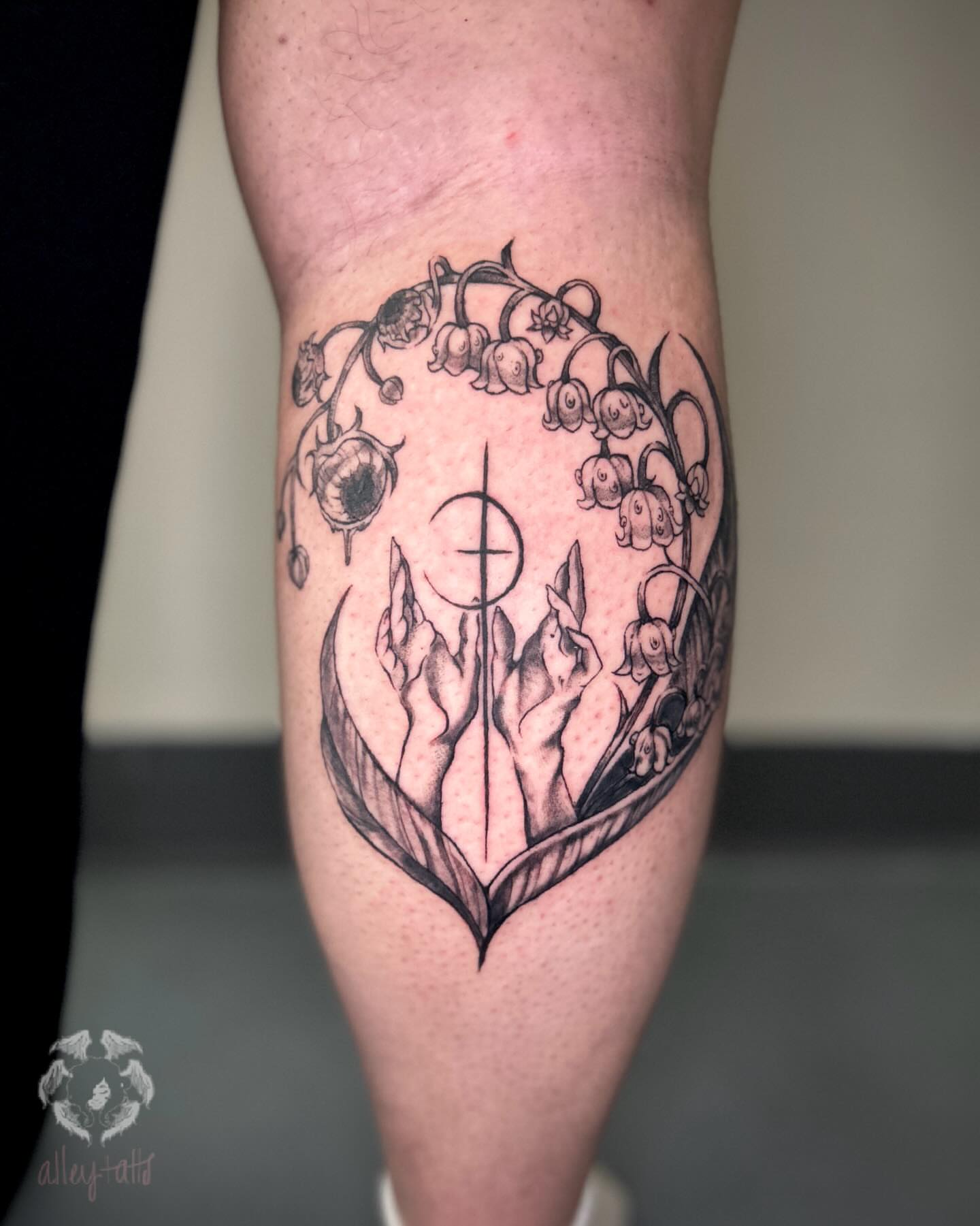 Lily of the valley and hands black and grey tattoo on the thigh by Alex