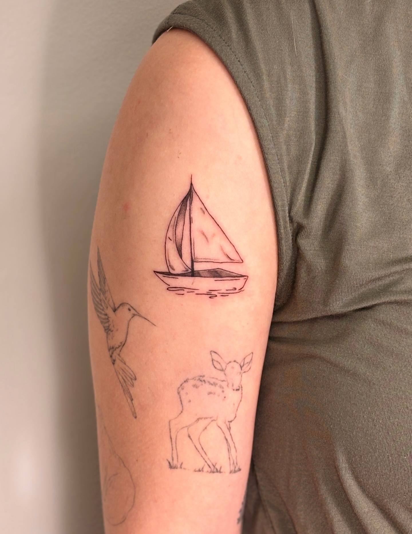 Sailboat, hummingbird, deer minimalist tattoo on the forearm by Maddie