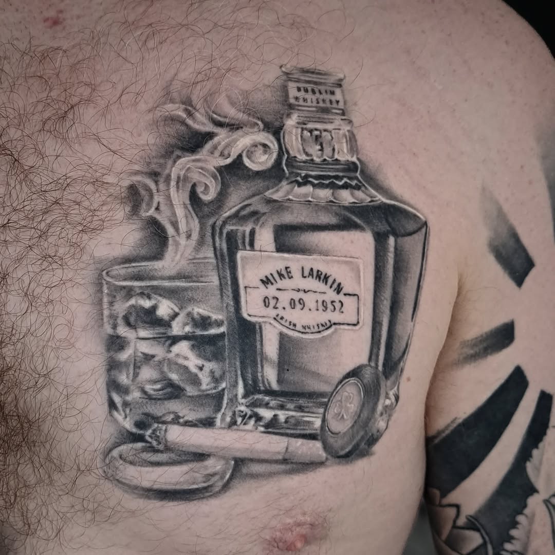 Whiskey bottle, glass, and cigar realism tattoo on the chest by Lindsay