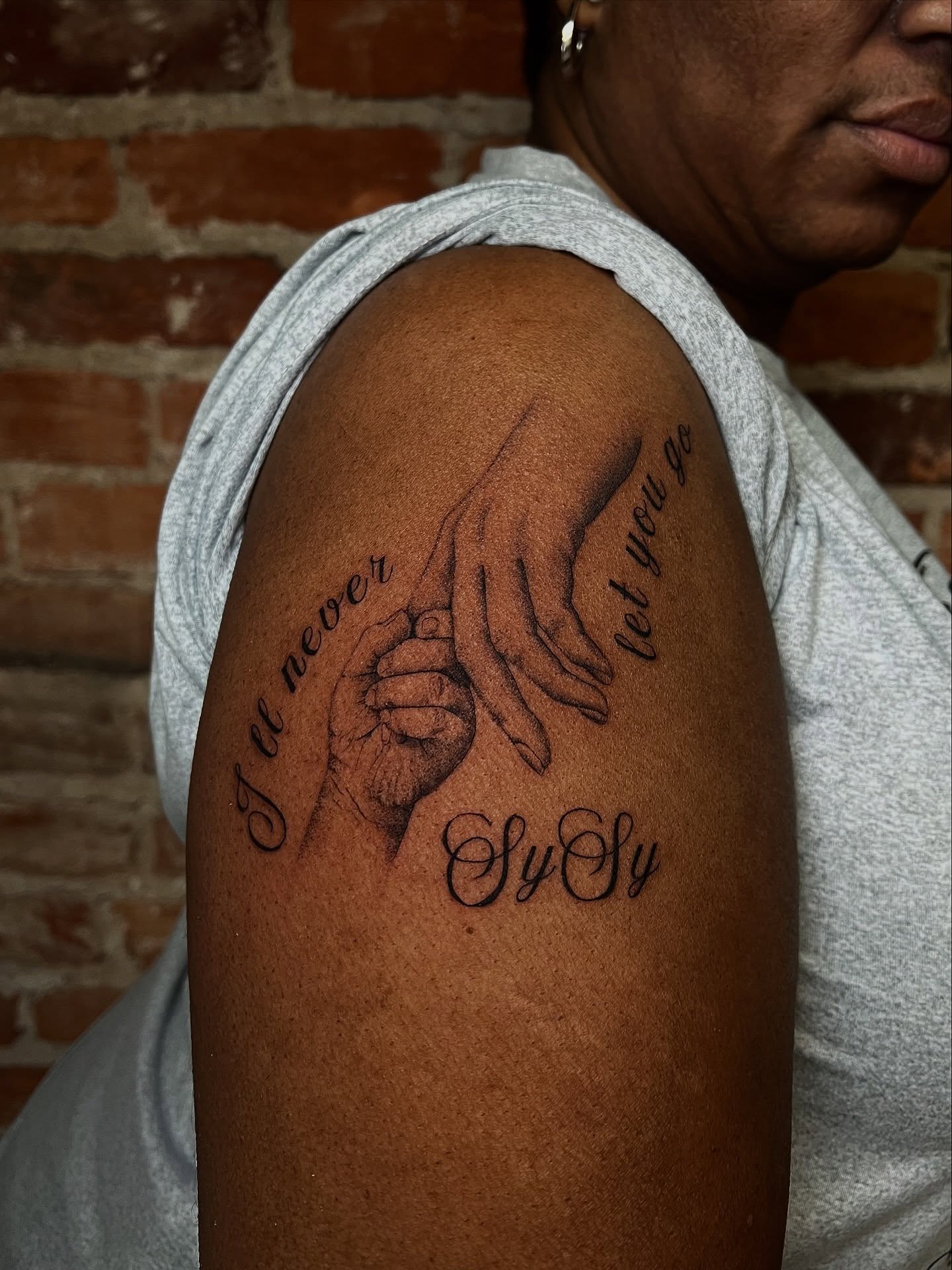 Holding hands black and grey tattoo on the shoulder by Uncomfy Comfort Tattoos LLC