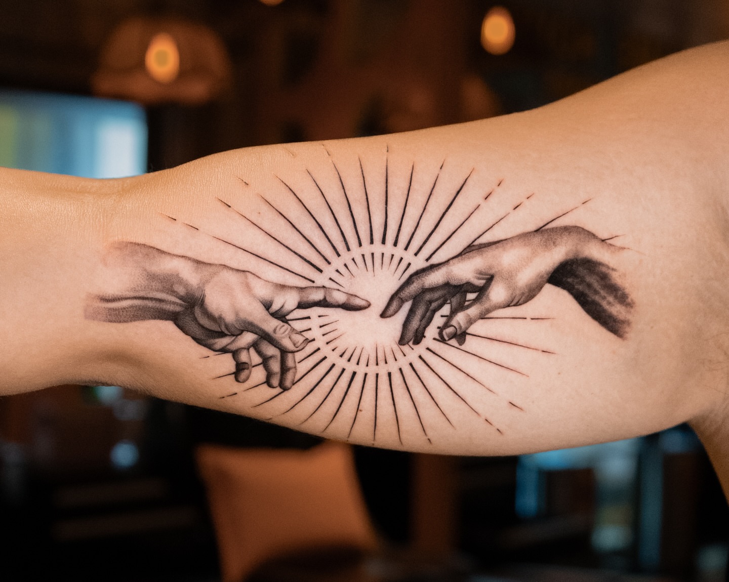 Hands reaching towards light black and grey tattoo on the forearm by Mateo
