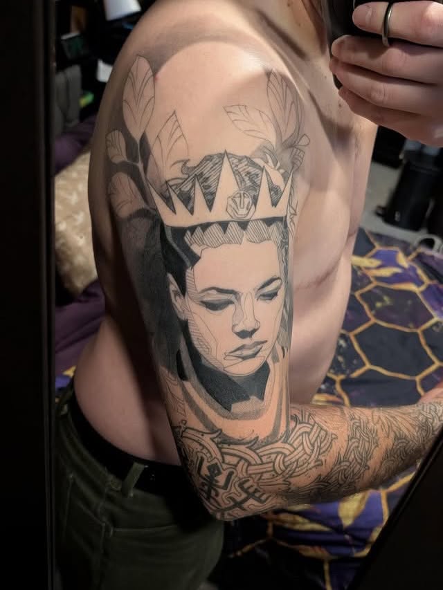 Portrait with crown realism tattoo on the upper arm by Rizzie D'Alterio