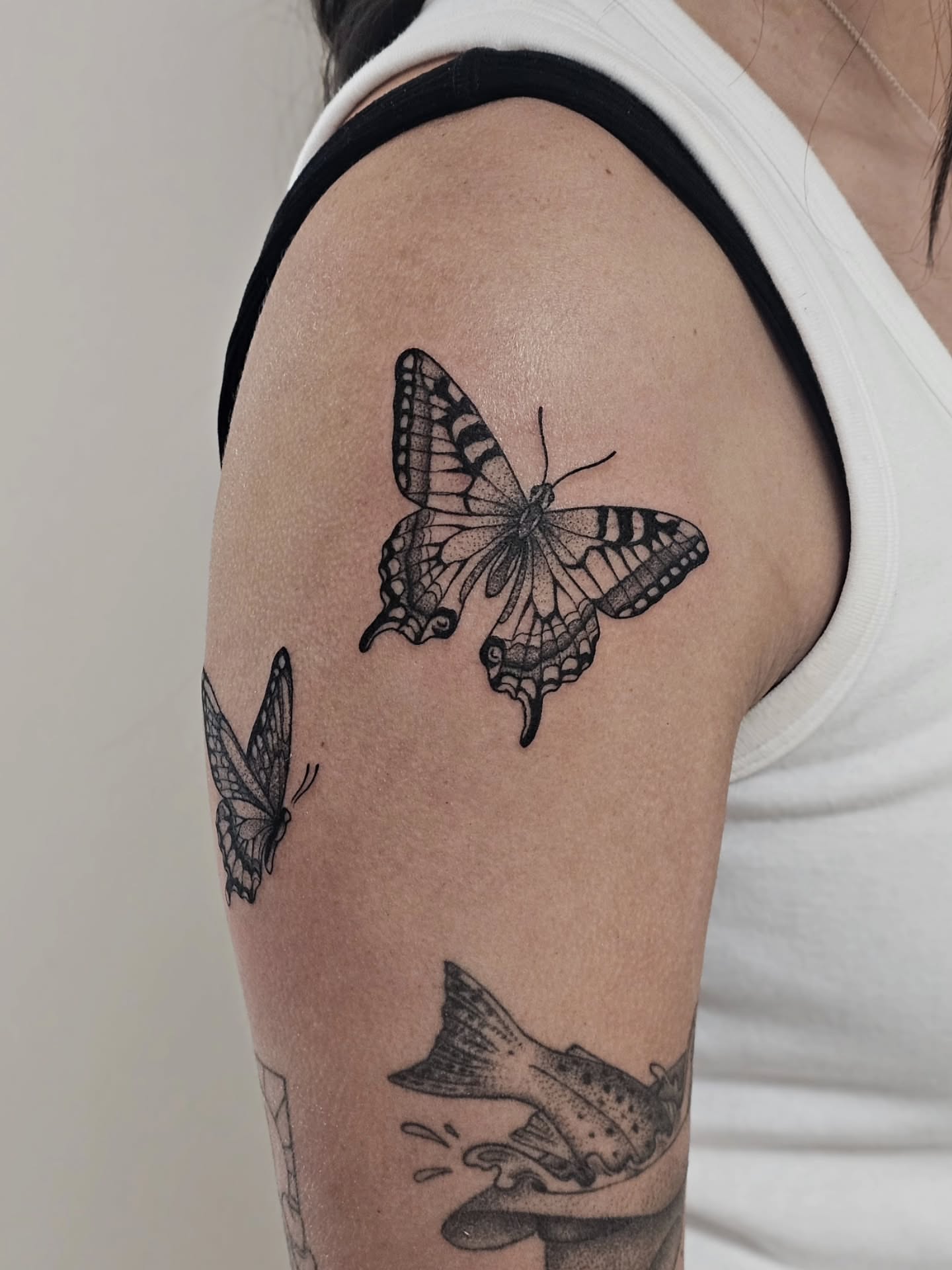 Butterfly black and grey tattoo on the upper arm by Kylie Lund
