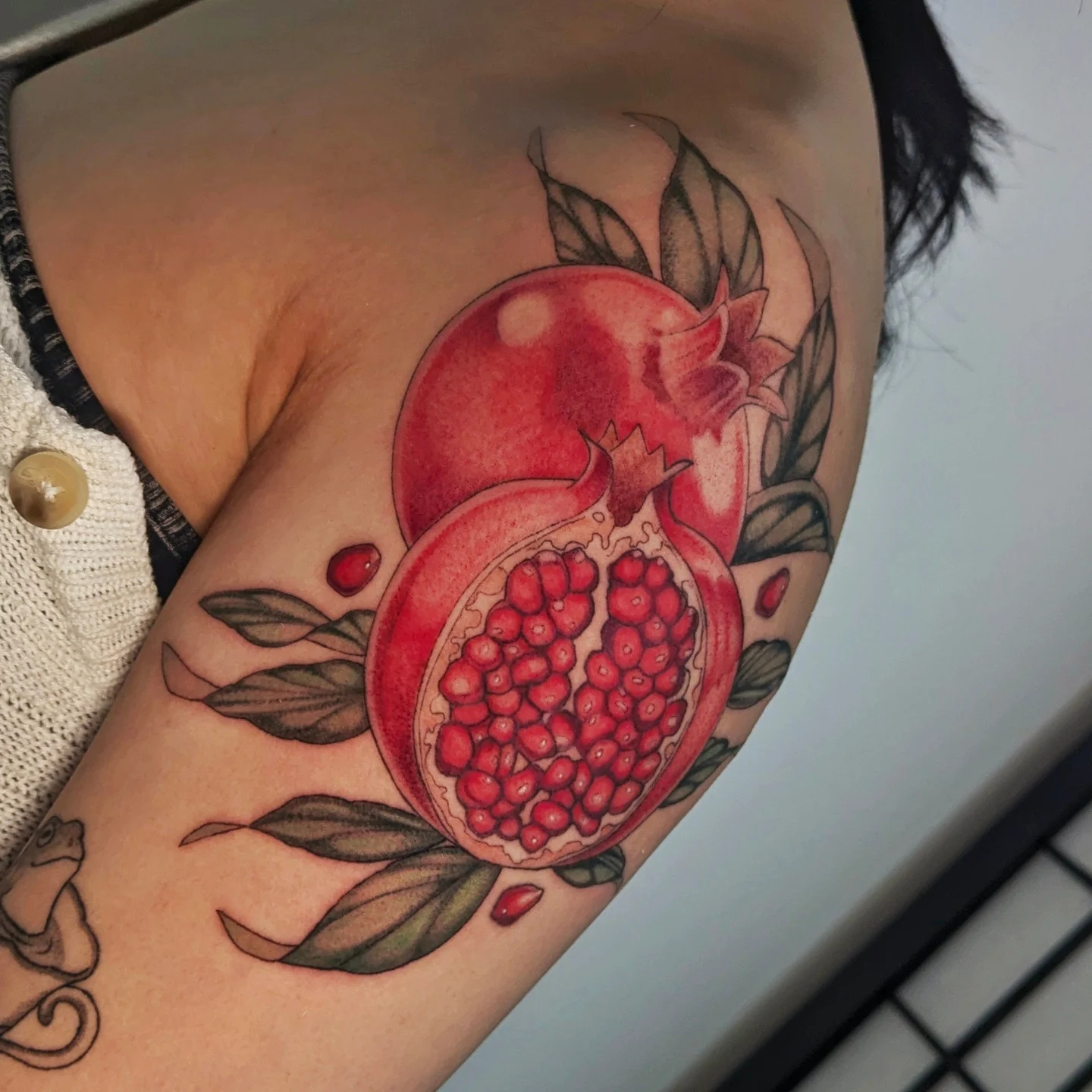 Pomegranate realism tattoo on the upper arm by Jasmine Dillon
