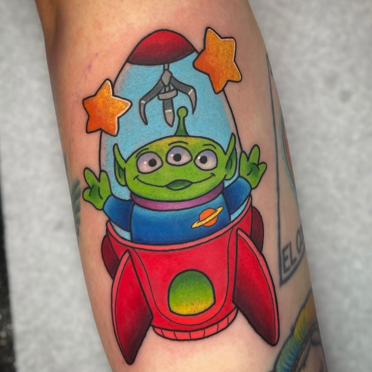 Alien in rocket illustrative tattoo on the forearm by Nicole Skalski
