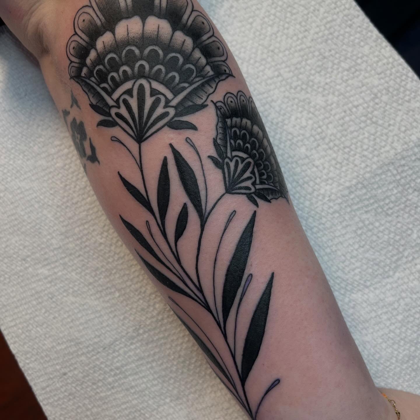 Floral arrangement black and grey tattoo on the forearm by Evan Voelker