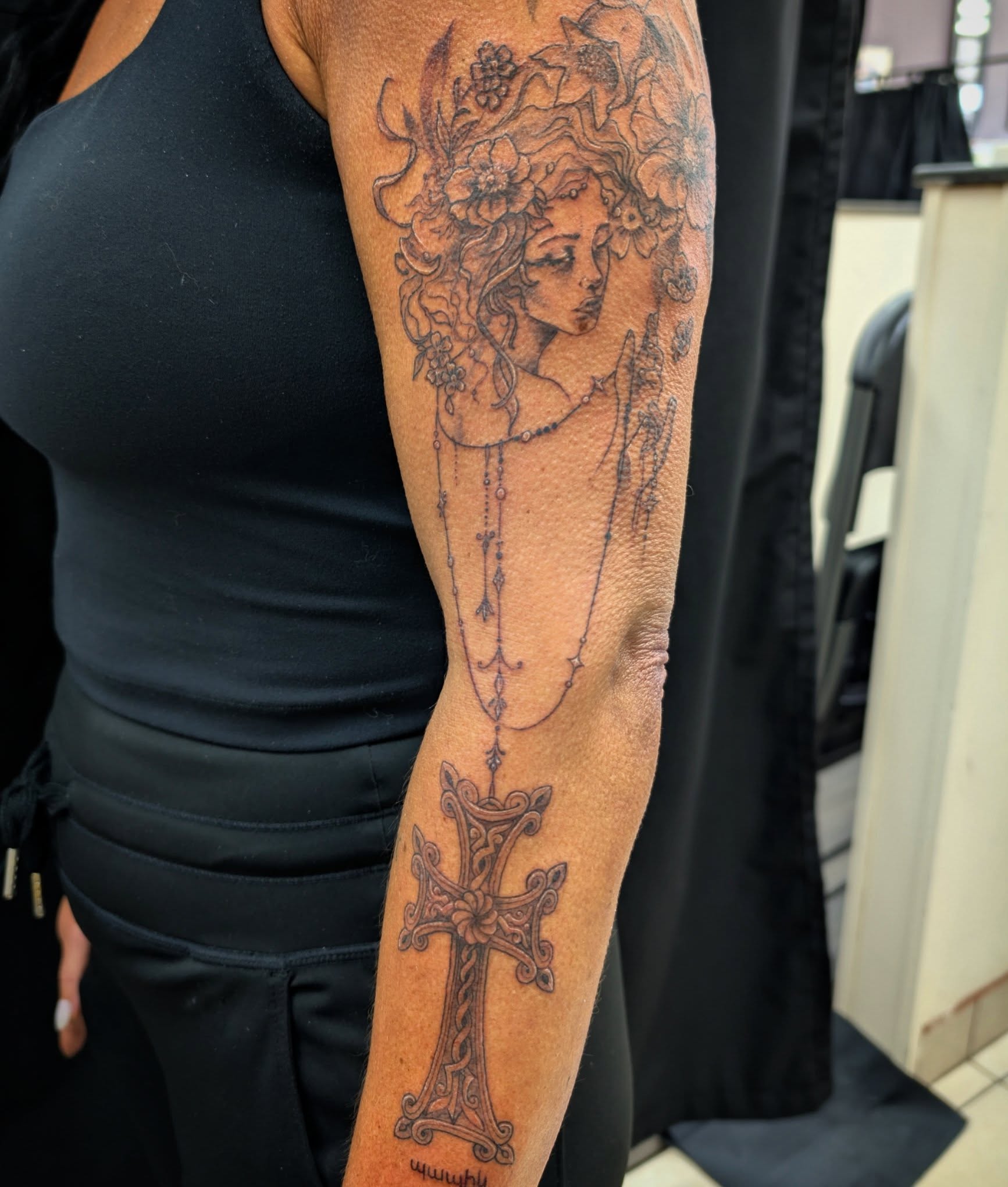 Woman with floral crown realism tattoo on the forearm by Katherine
