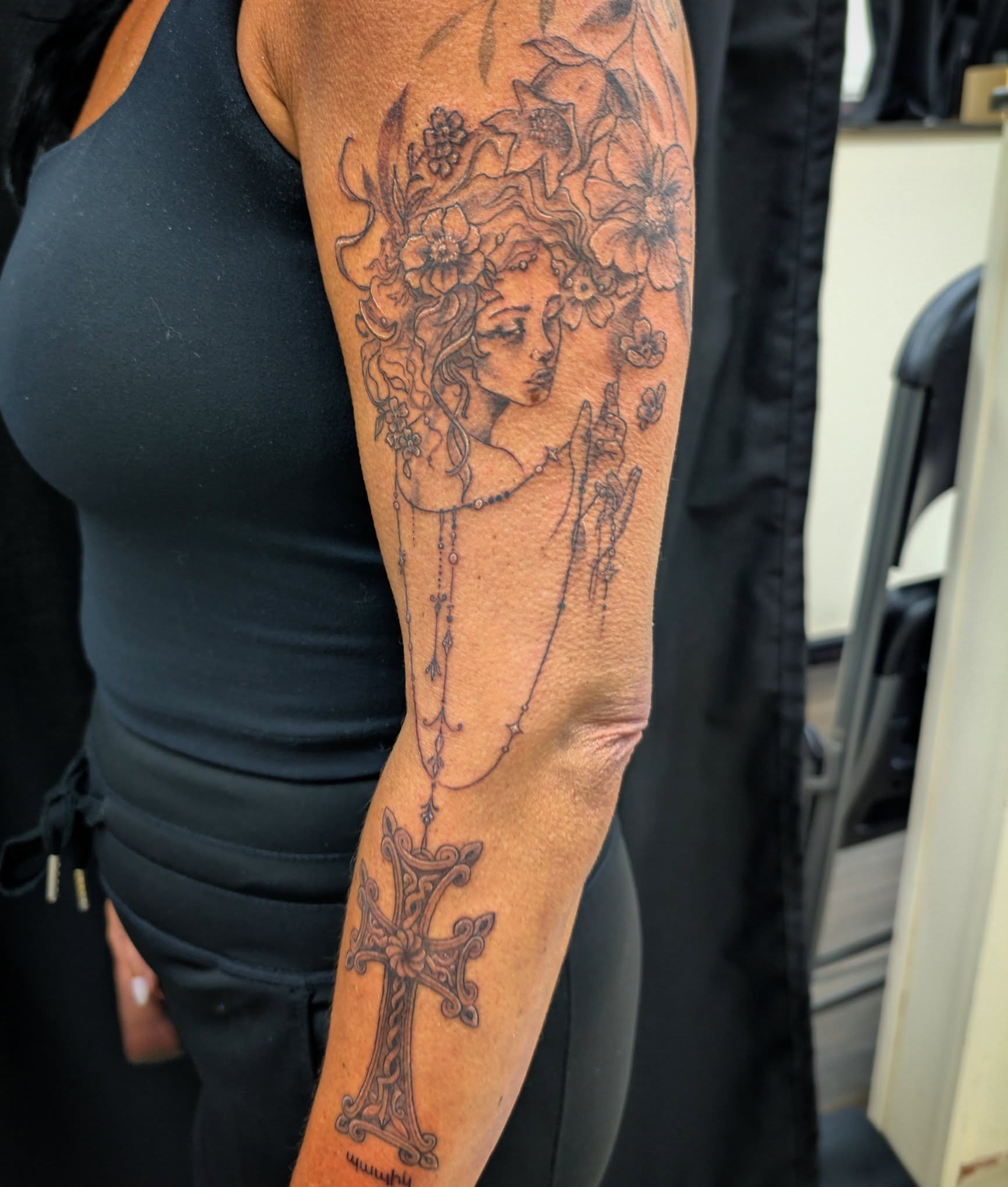 Floral woman with cross realism tattoo on the forearm by Katherine